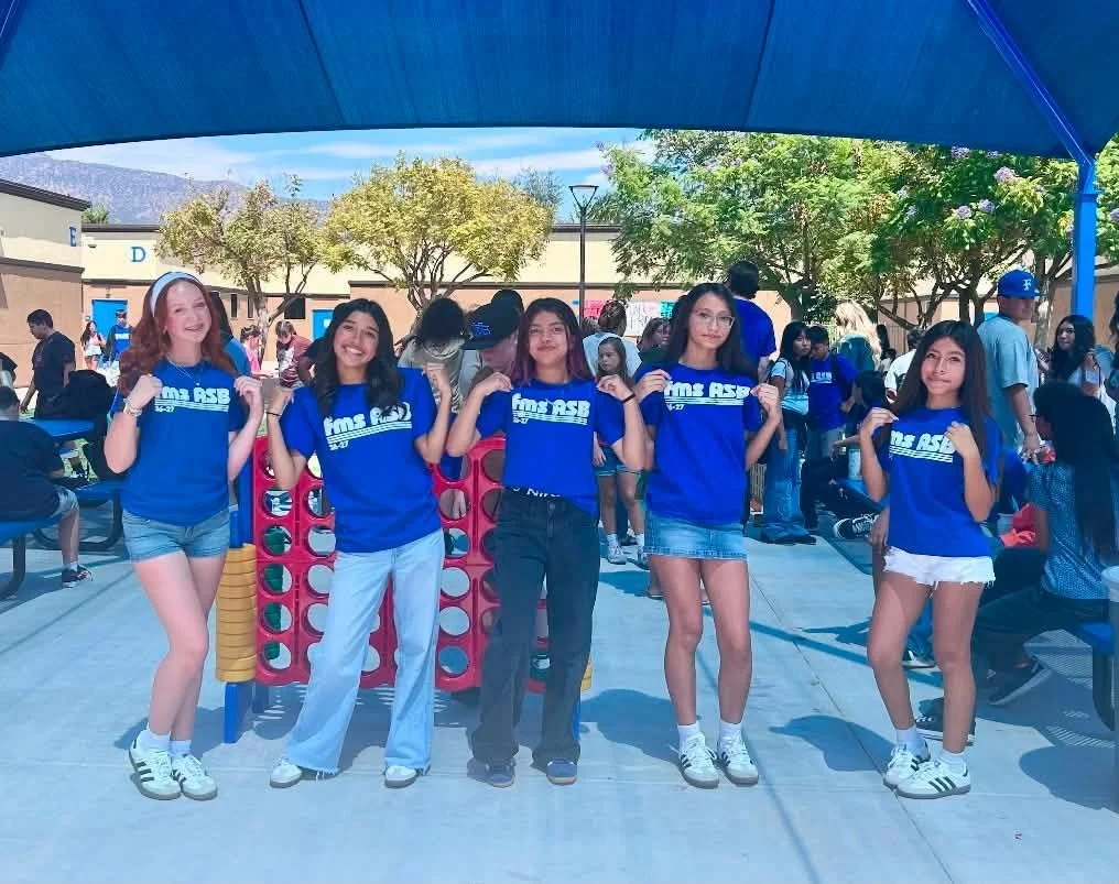 ASB student leaders pose in their blue shirts beside the game area.