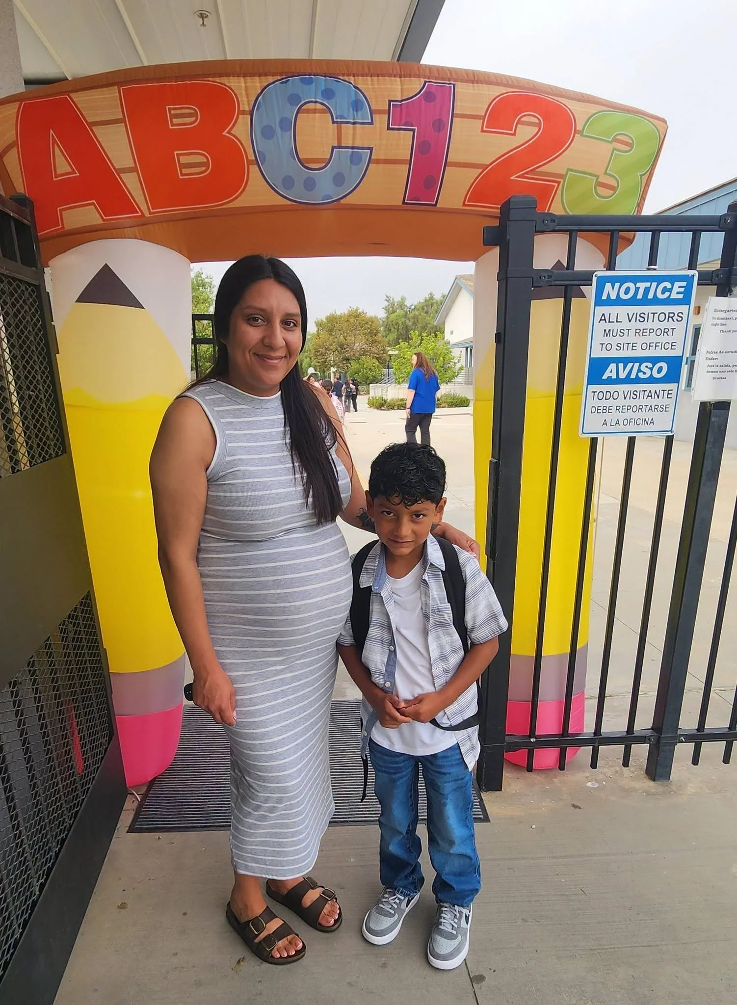 An adult and student stand beneath an ABC123 welcome arch.