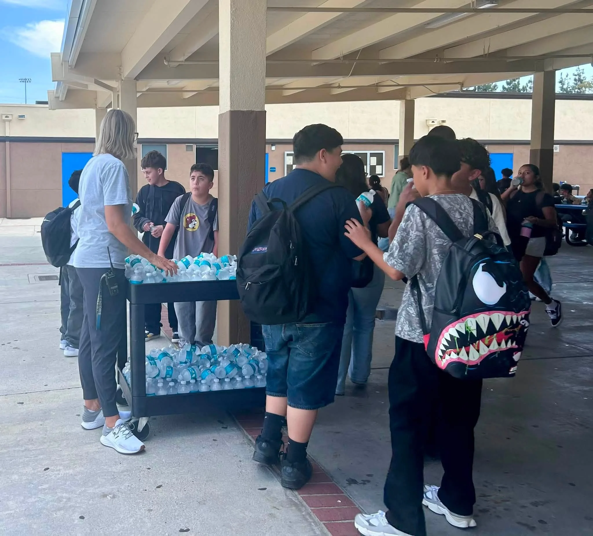 Bulldogs gather around a cart of cold water during warm weather.