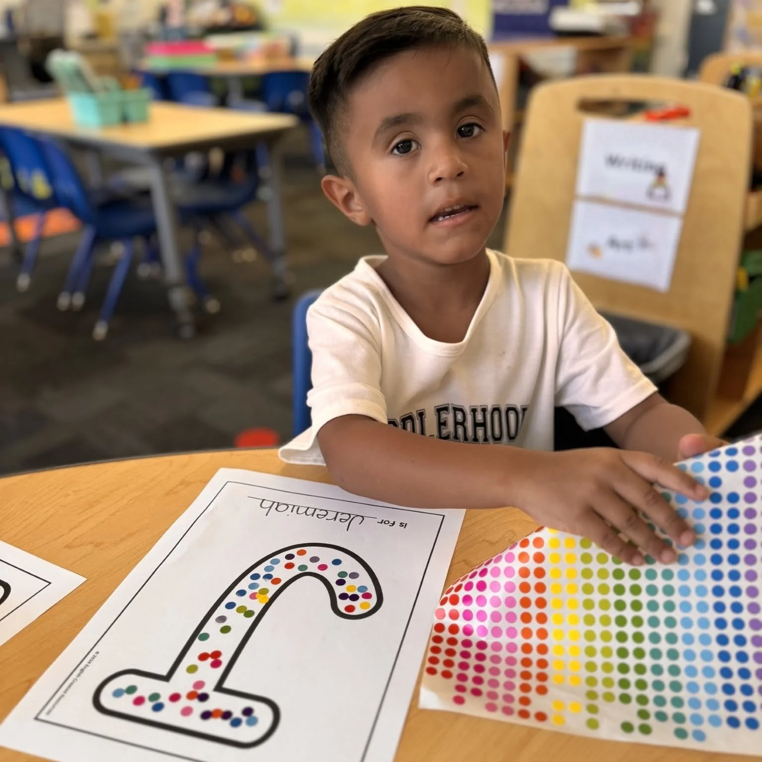 A student adds dot stickers to the first letter of their name.
