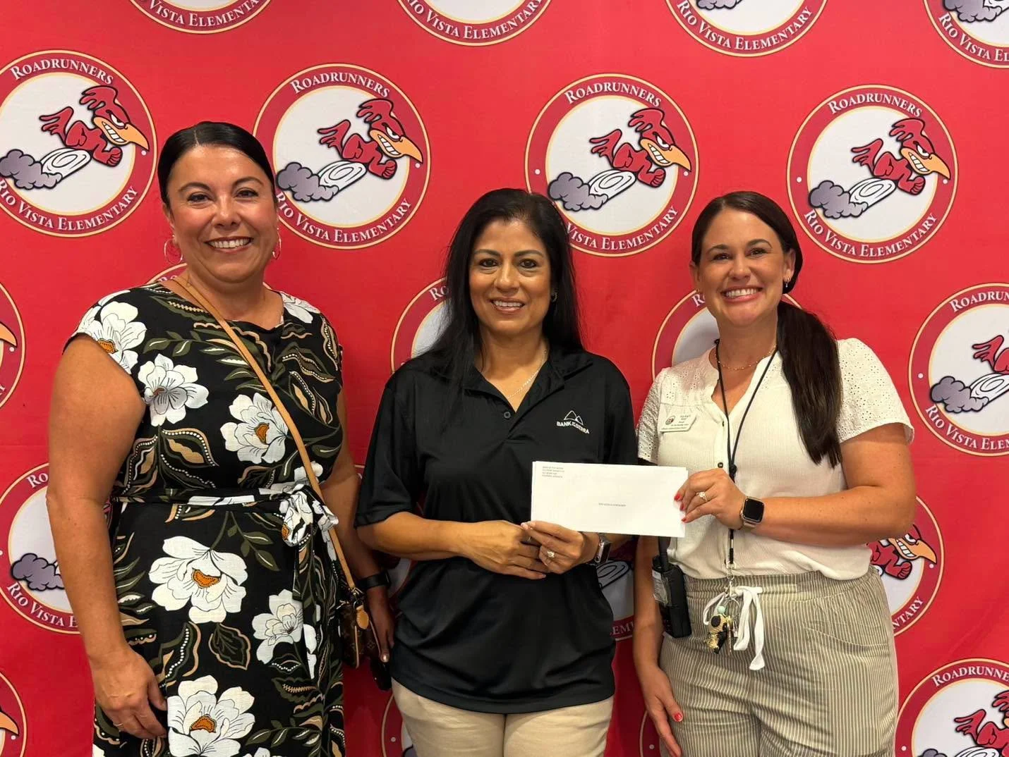 School staff and a bank representative hold the donation envelope.