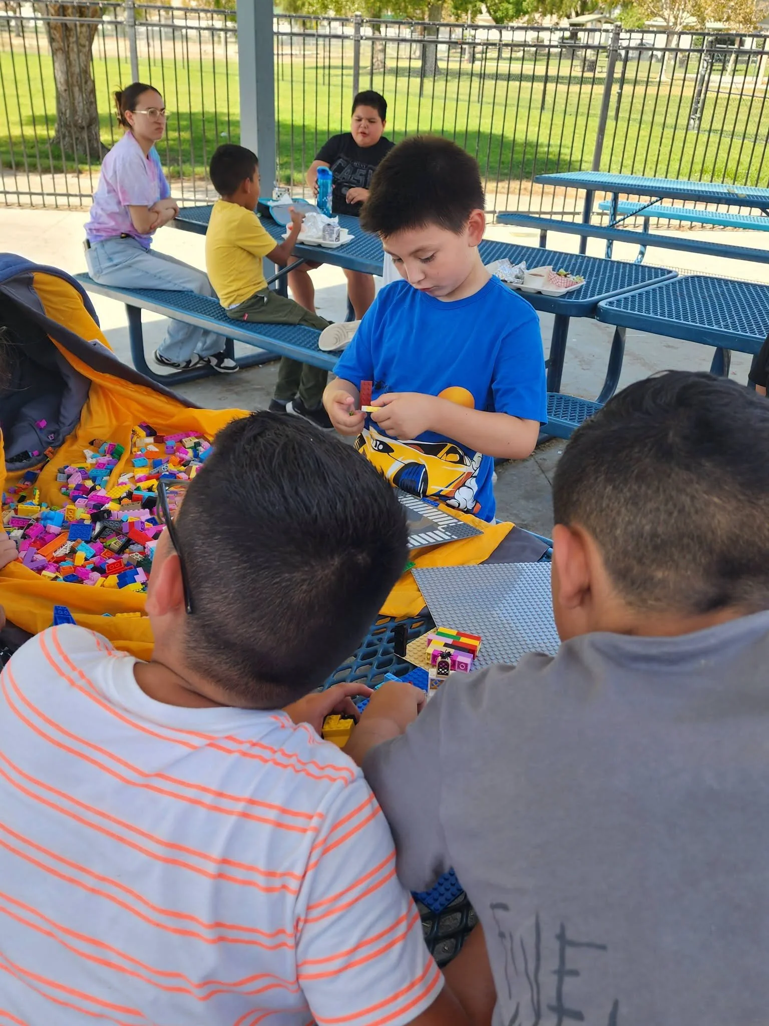 A student in a blue shirt builds with Lego bricks alongside classmates.
