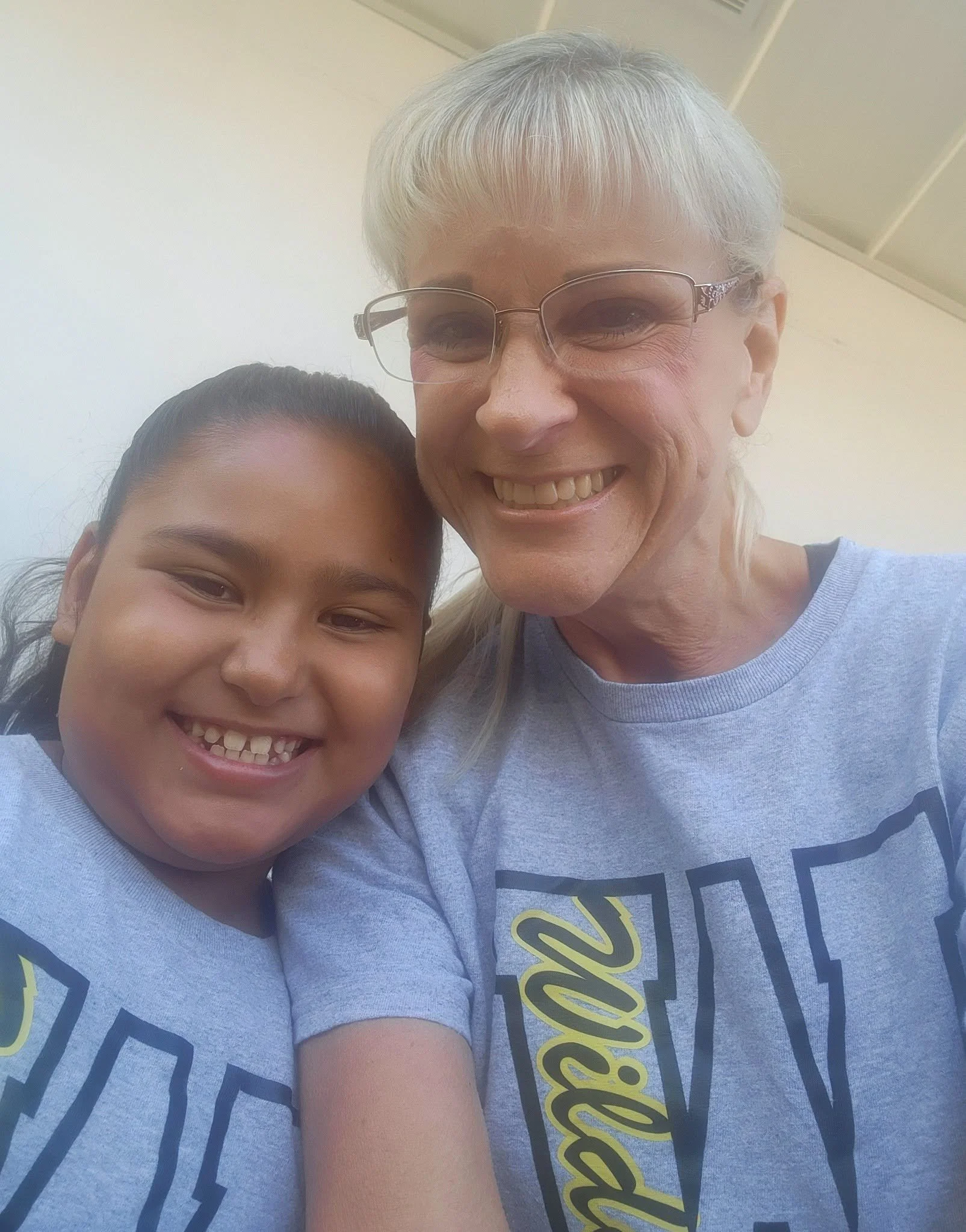 A student and adult smile together in matching gray Wildcats shirts.
