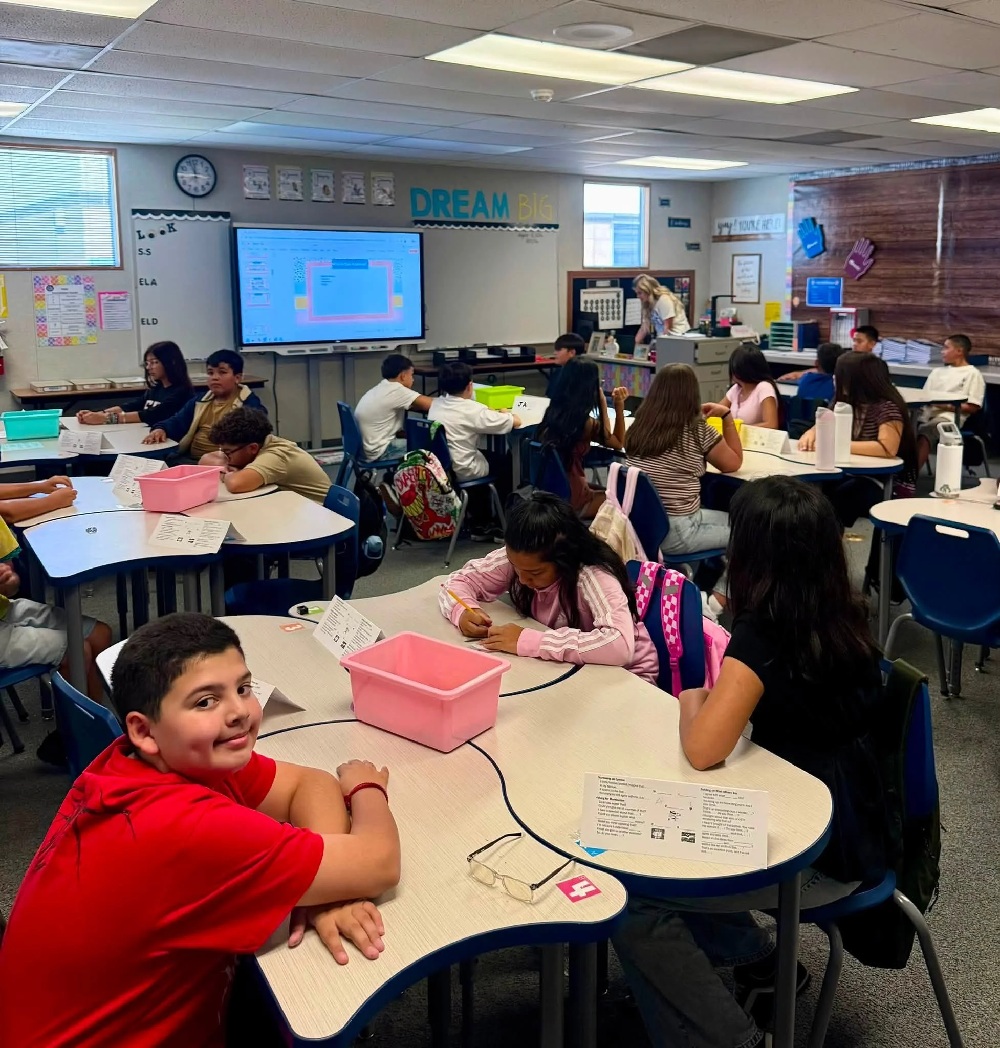 Students work at classroom tables on the first day of school.