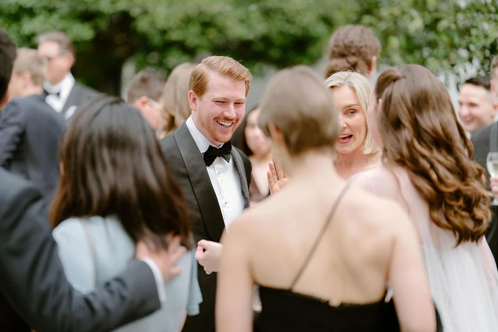 People in formal attire socializing at an outdoor event, with a smiling man in a tuxedo at the center. Hunter Valley wedding photographer couple portrait
Bowral wedding cinematography vineyard film still
Newcastle wedding candid photos