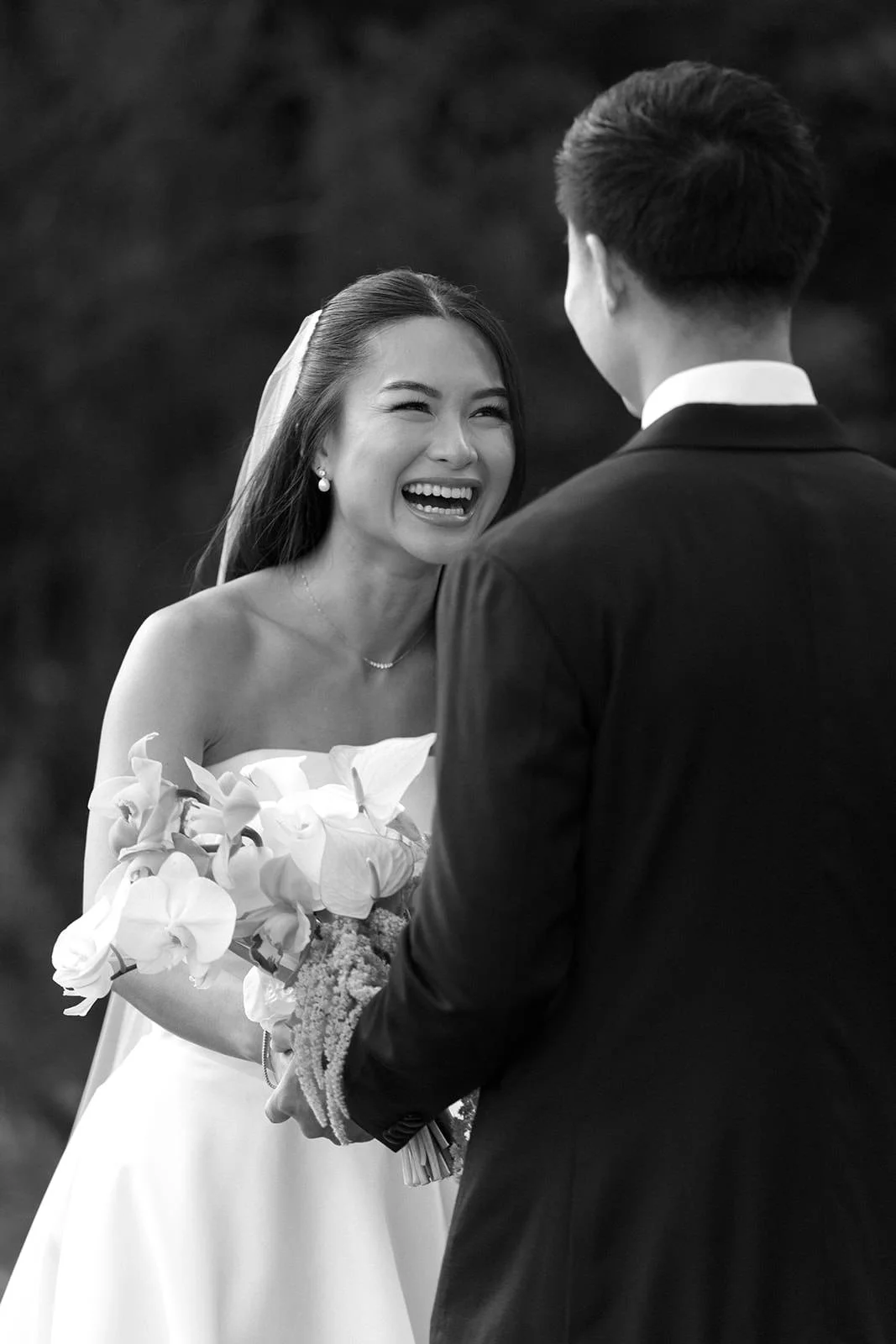A joyful bride laughing while holding a bouquet, facing a groom during their wedding ceremony outdoors. Hunter Valley wedding photographer couple portrait
Bowral wedding cinematography vineyard film.