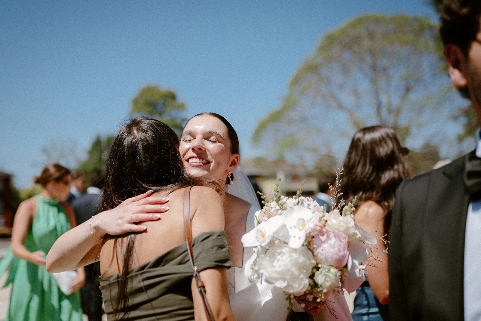 Two women hugging during a wedding celebration outdoors with other guests in the background. Hunter Valley wedding photographer couple portrait
Bowral wedding cinematography vineyard film still
Newcastle wedding candid moment natural storytelling