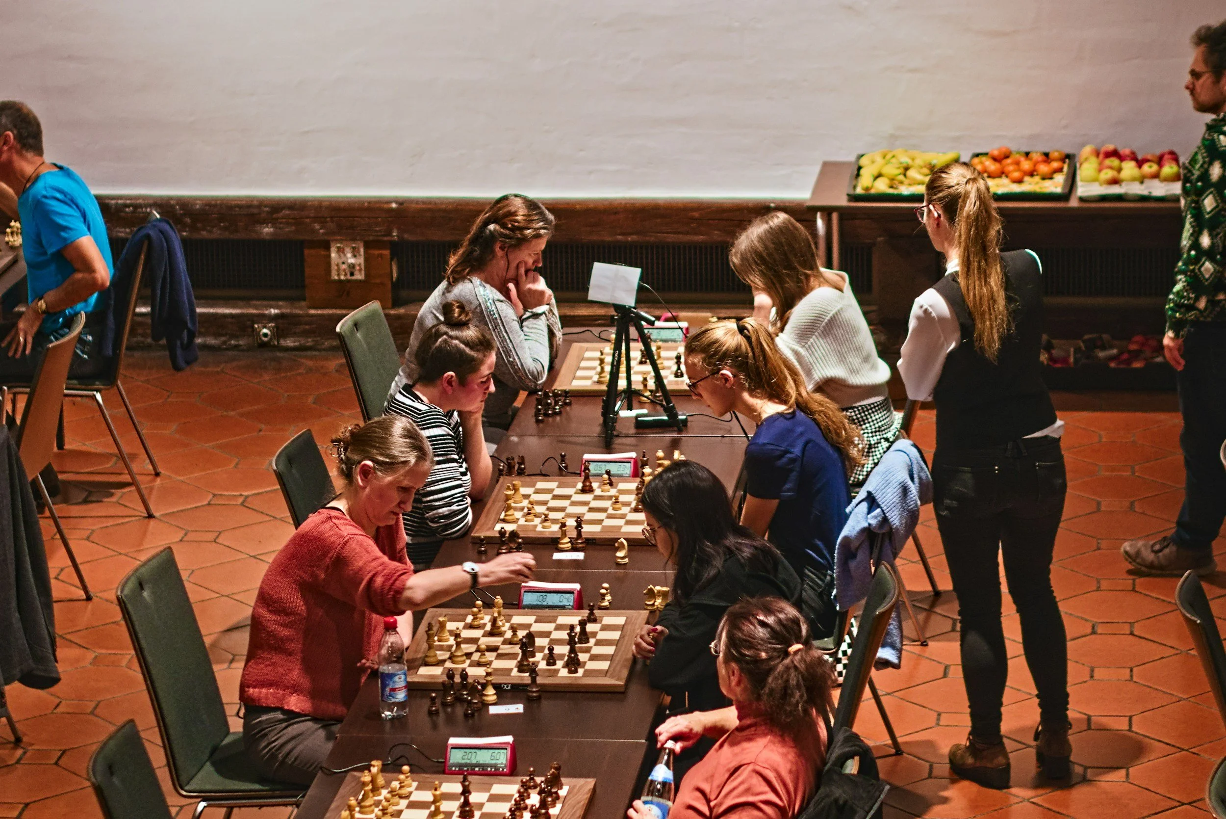 Mensen die schaken tijdens een competitie. Ze zitten op stoelen aan een tafel met schaakborden en klokken.