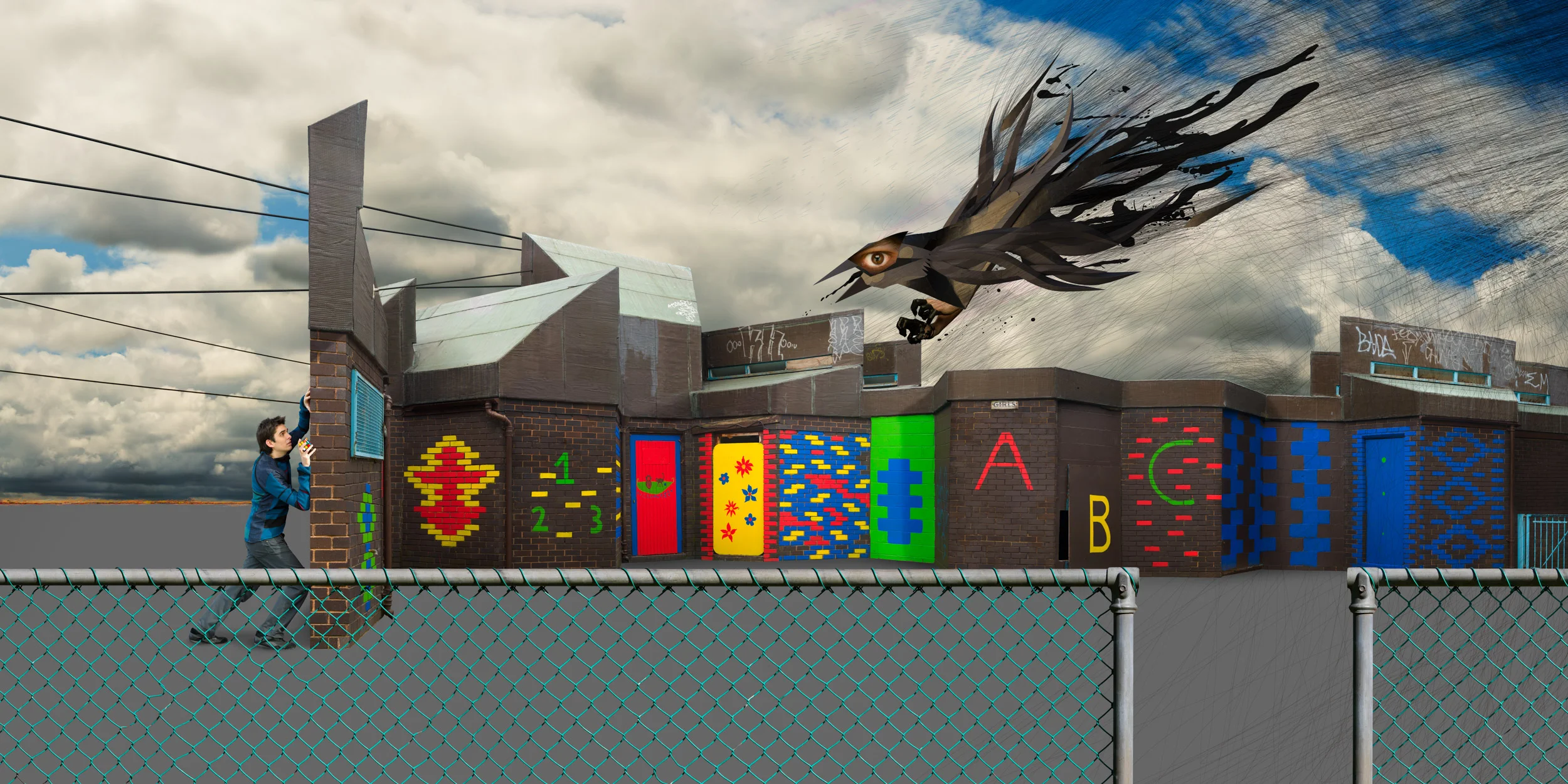 A boy running behind a chain-link fence in front of a graffiti-covered brick wall with colorful abstract designs and symbols. A large dark creature with an eye and flowing hair is flying in the sky above the wall.