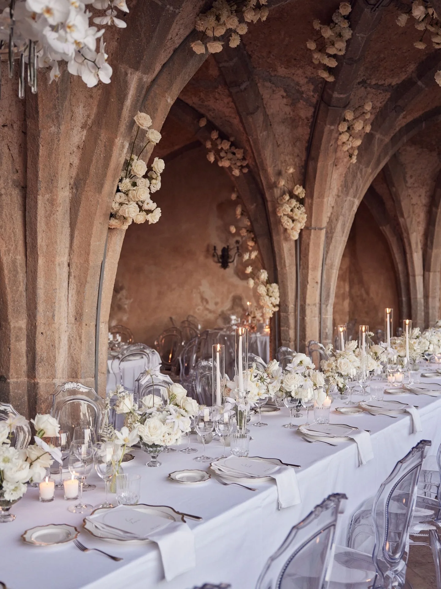 Layered white florals climbing through Villa Cimbrone&rsquo;s stone arches, custom orchid installations suspended overhead and a candlelit imperial table stretching through the vaulted corridor overlooking the Amalfi Coast. Every detail was intention