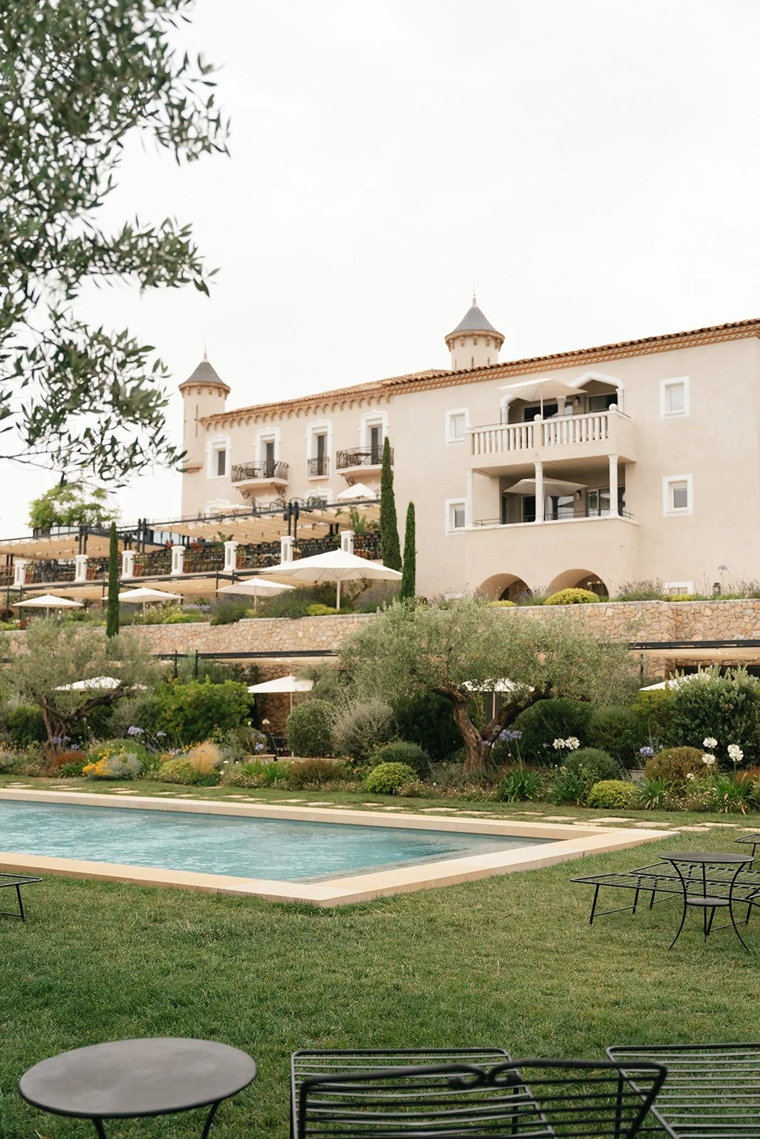 A pale villa surrounded by olive trees and a swimming pool.