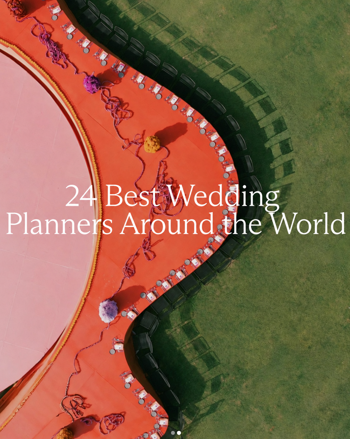 Aerial view of a curved orange reception table with colorful flowers and surrounding chairs on a lawn.