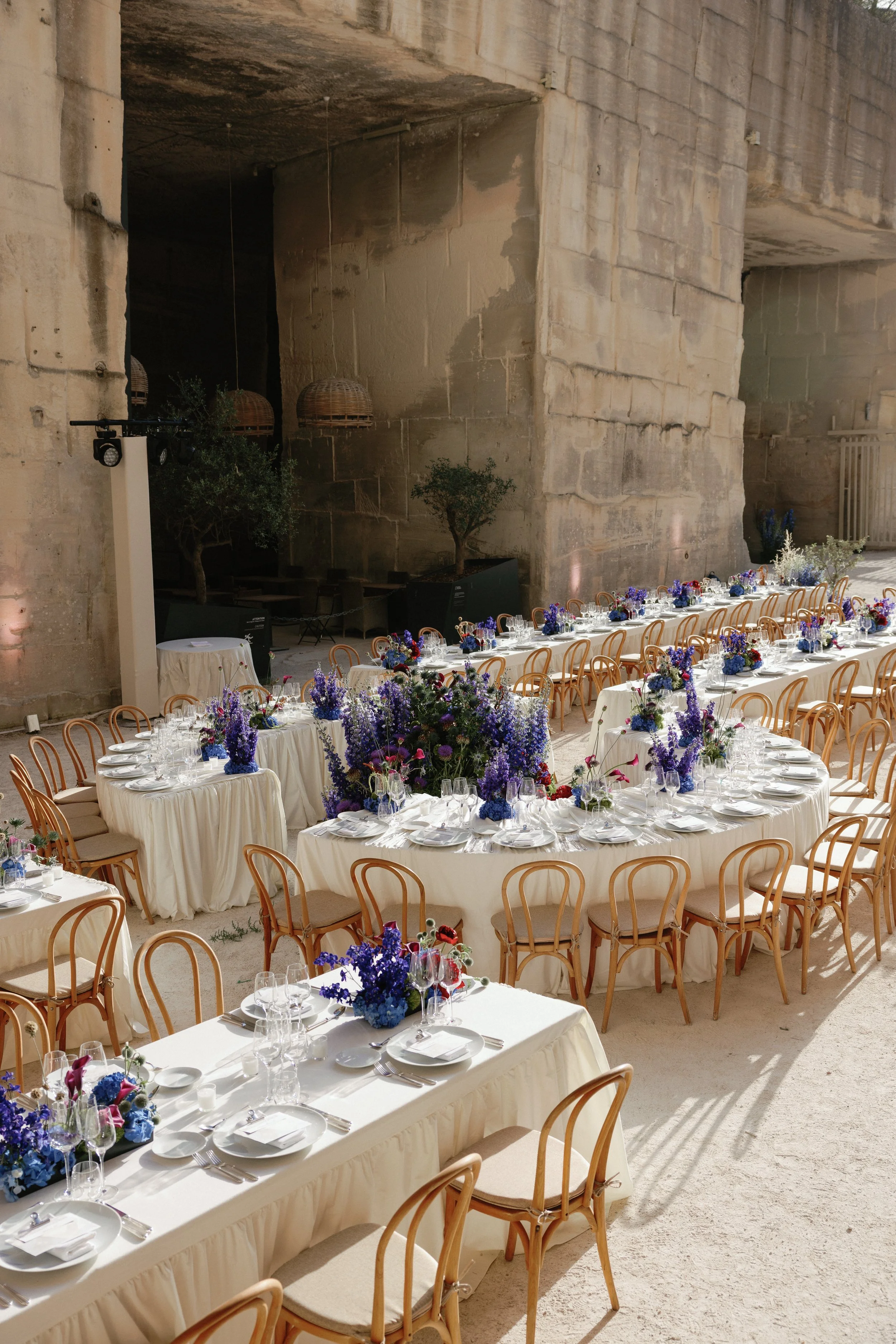 Wedding reception tables with blue flowers in a stone quarry.