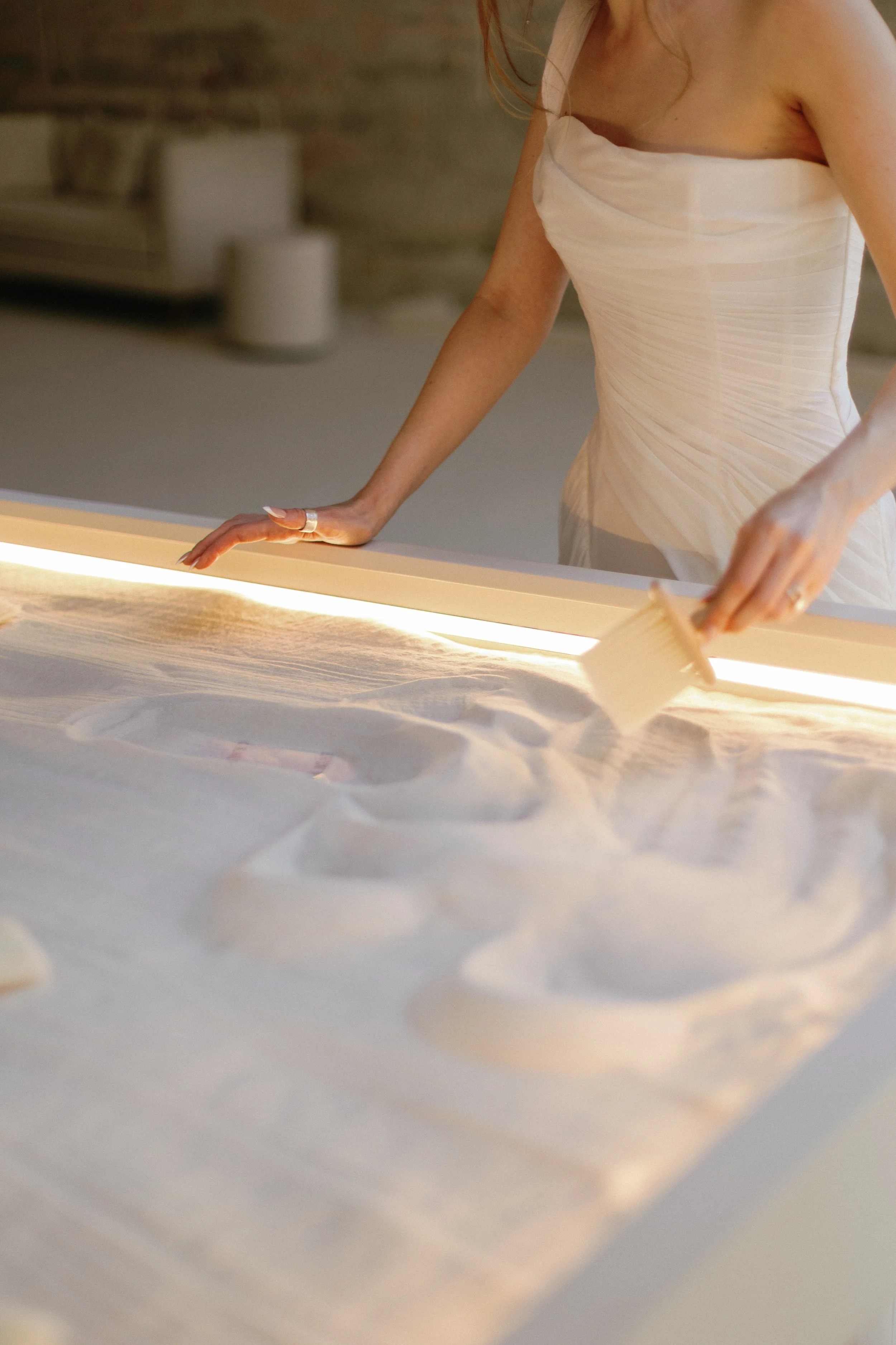 A bride beside an illuminated sand installation.