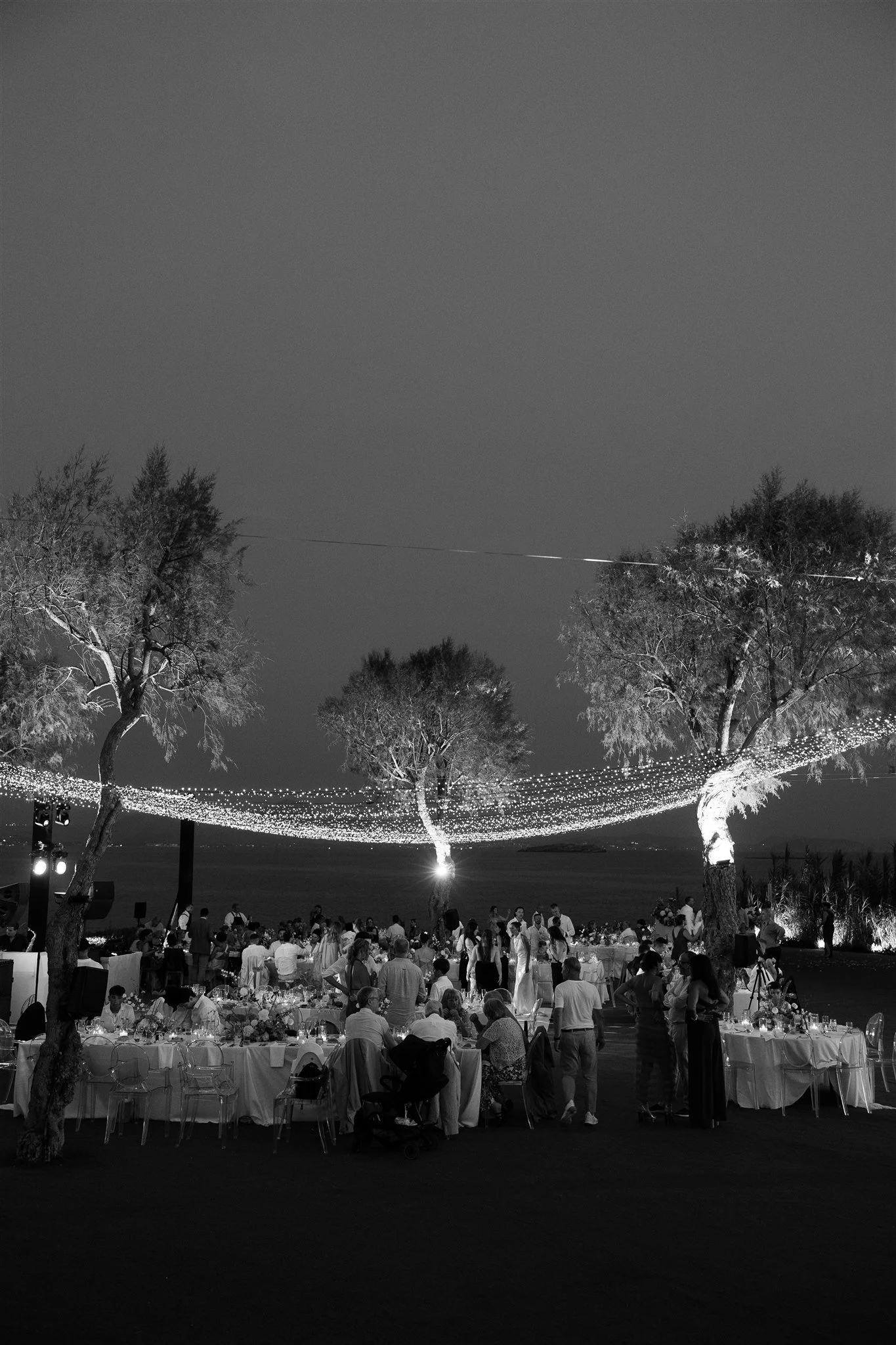An outdoor wedding reception beneath a canopy of fairy lights.