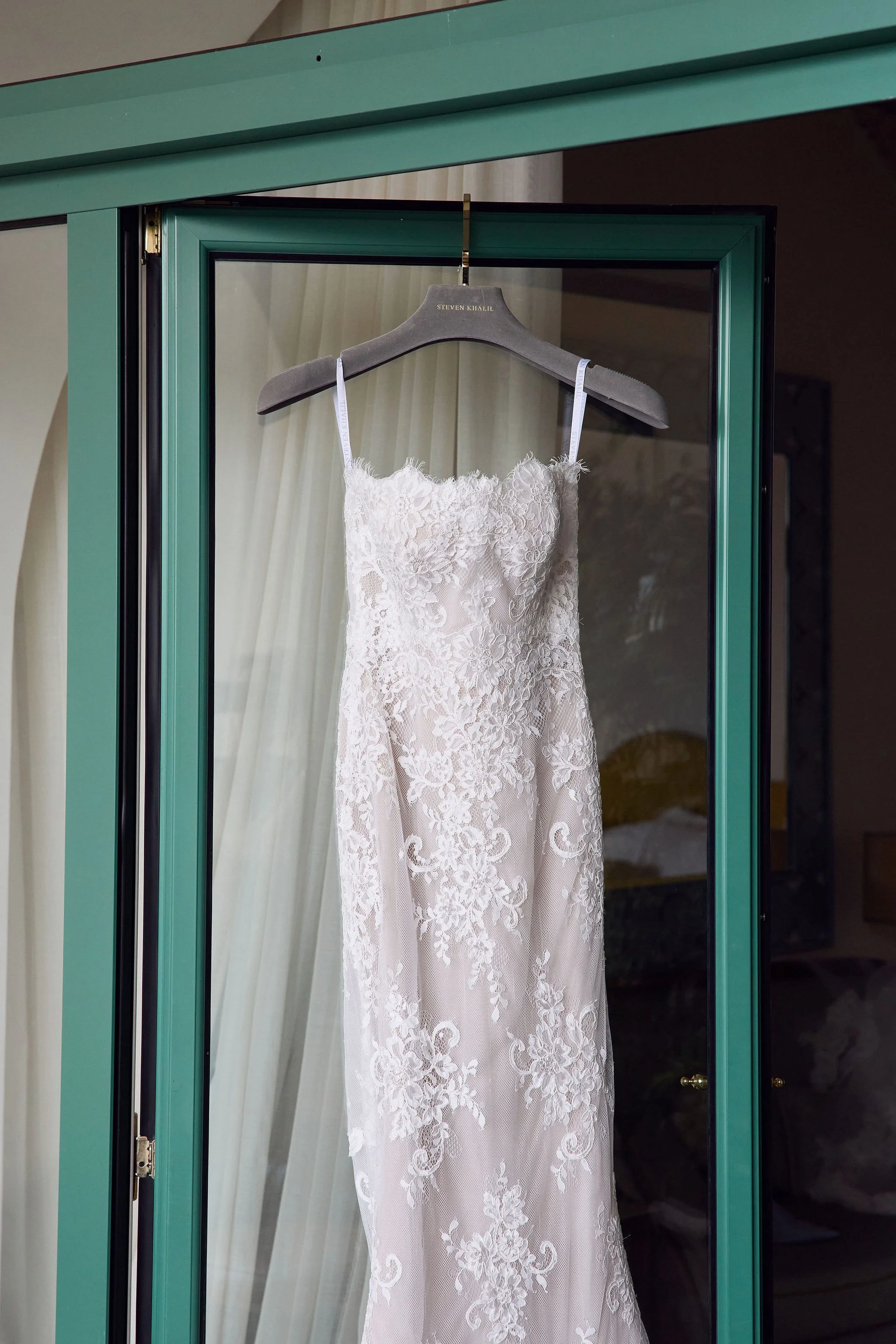Wedding dress hanging inside a green wardrobe.