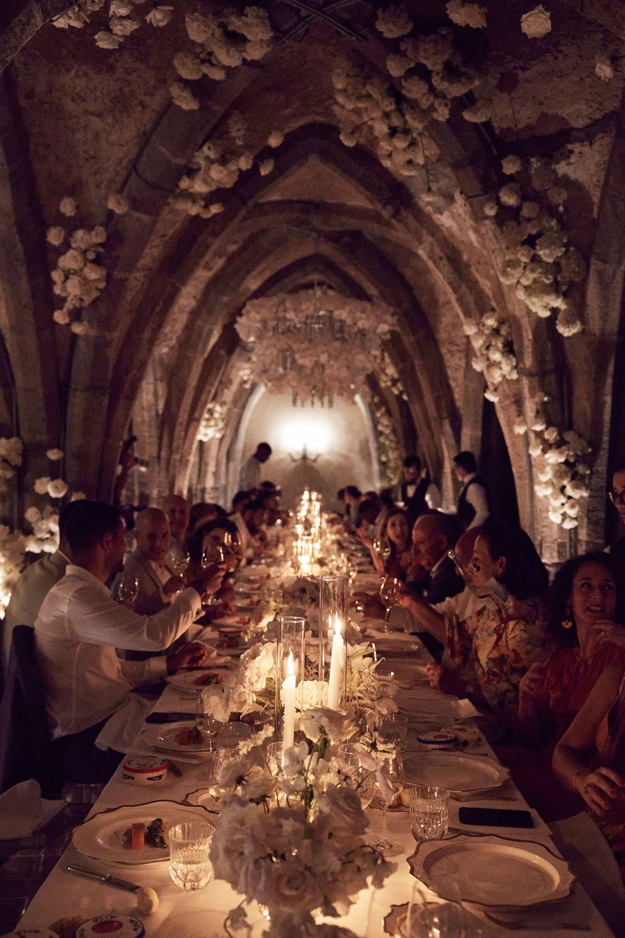 Guests raise their glasses at a candlelit wedding dinner.