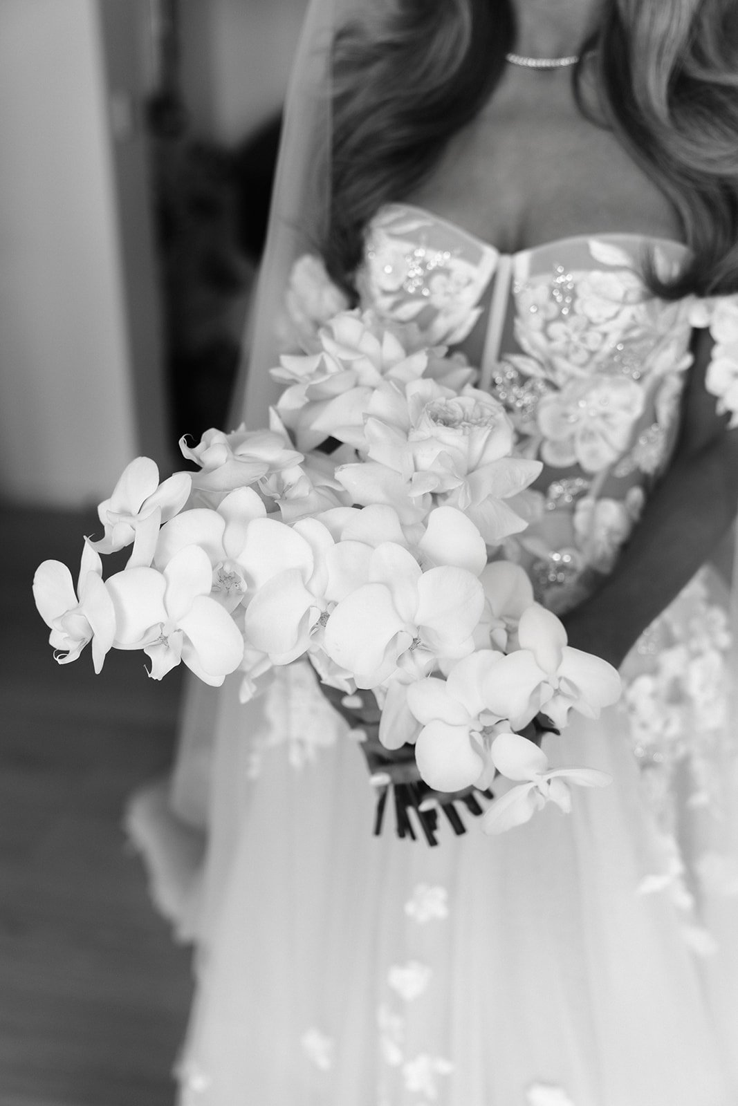 A woman in a wedding dress holding a bouquet of white orchids.