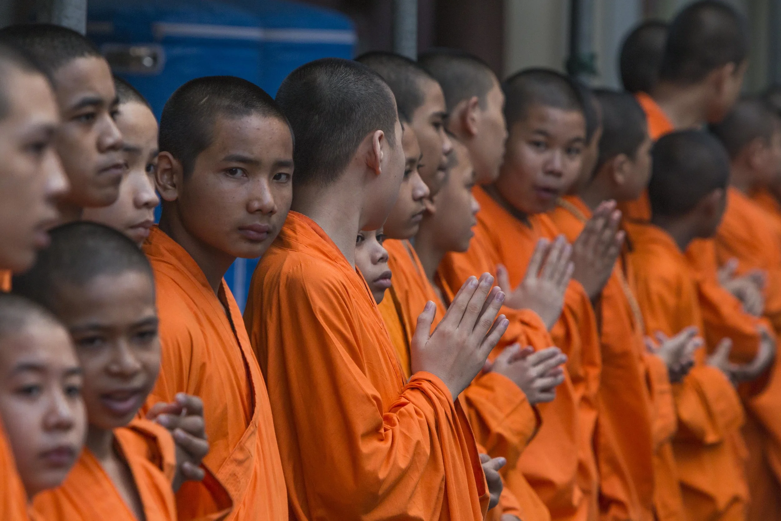 Novice monks from the Wat Mangkon Kamalawat monastery stand with hands clasped performing a wai