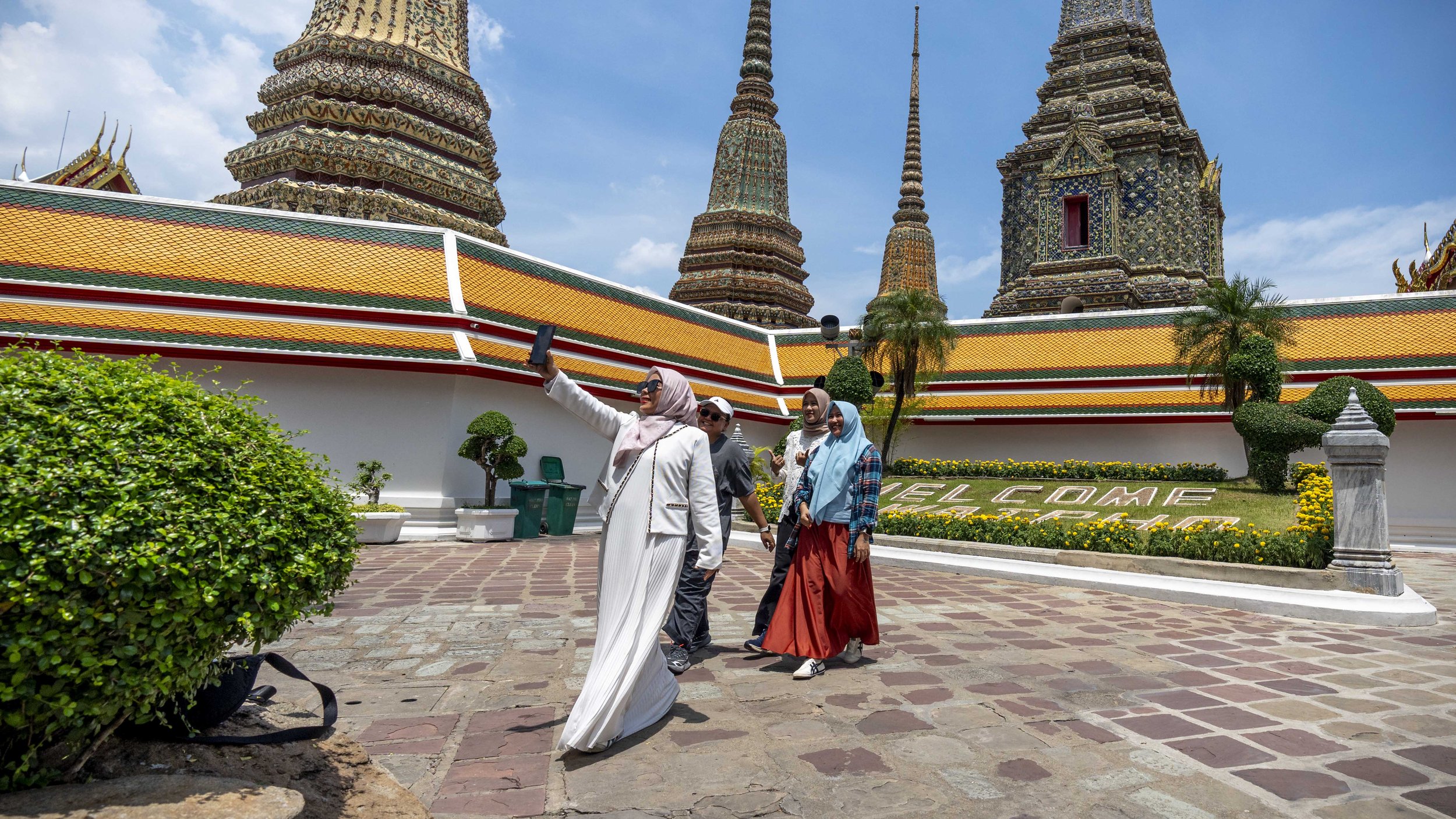 Muslim women wearing full hijab walk and pose while making smartphone videos on the grounds of Wat Po in Bangkok, Thailand - For Nikkei Asia
