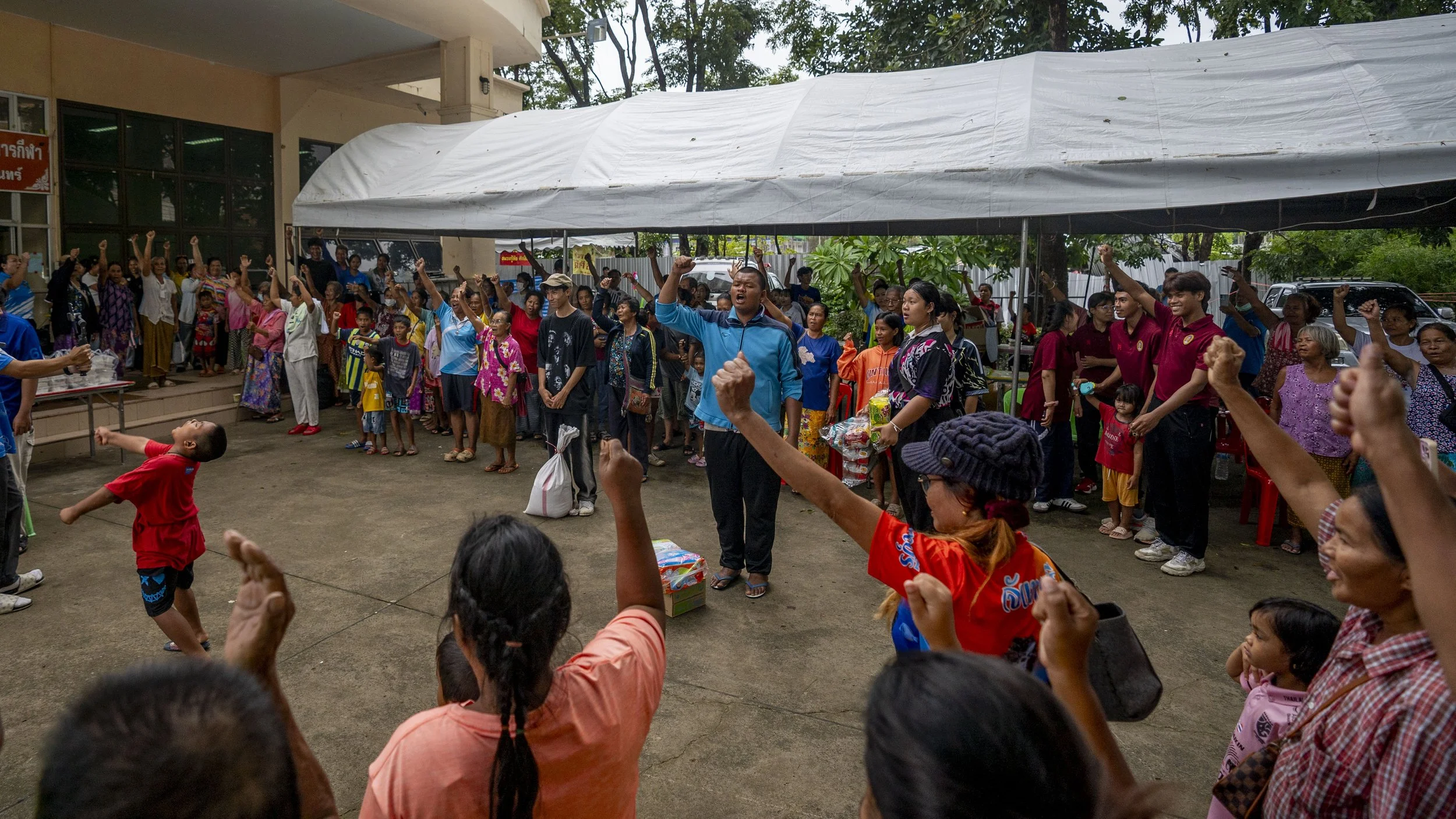 Residents of Surin sheltering in an evacuation center stand and raise their fists after singing the Thai national anthem at 6pm on July 26th, 2025.