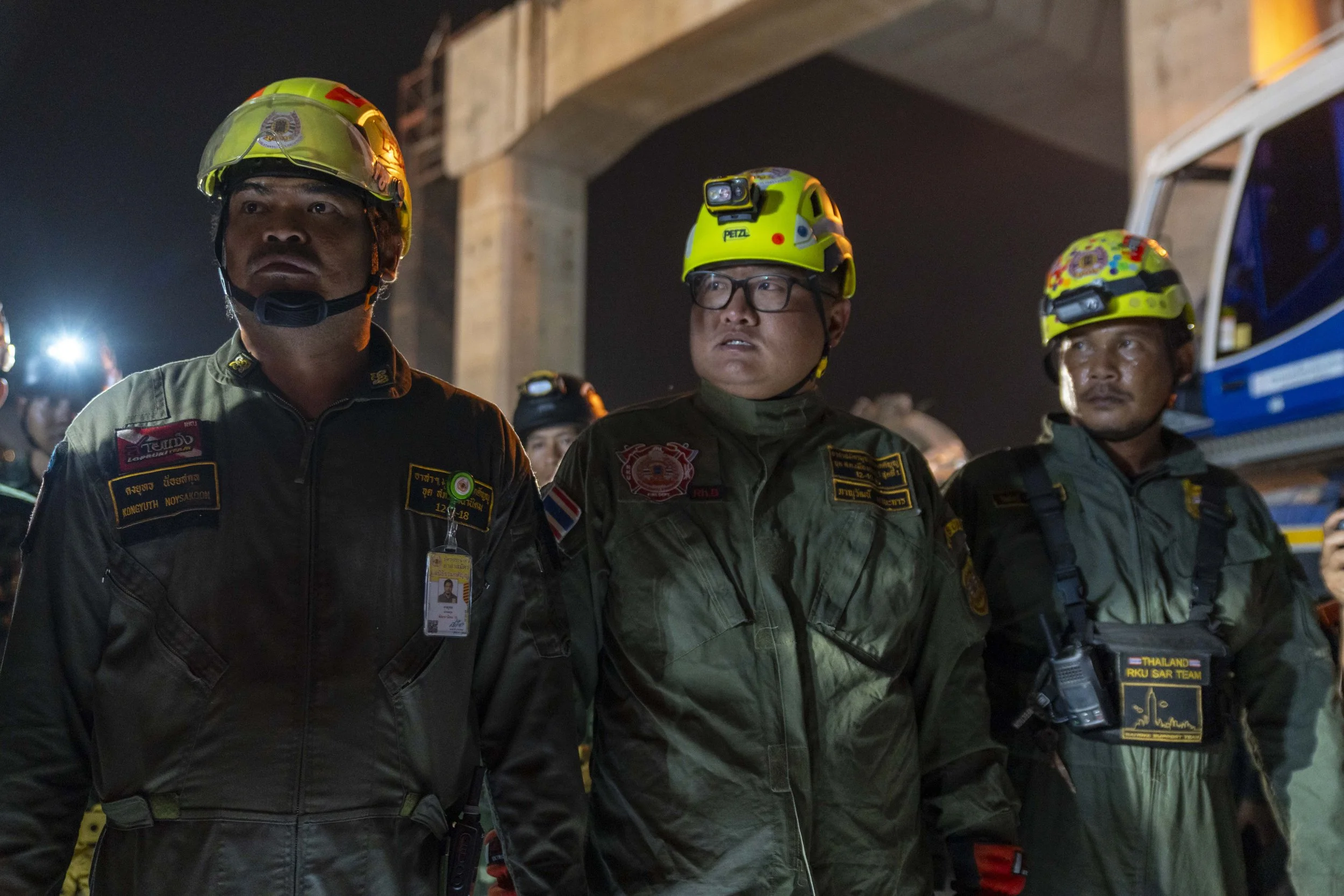  January 14, 2026: Search and rescue workers line up after concluding work for the night inspecting a damaged train car which was crushed by a falling crane while the train was was moving underneath the Thai-Chinese high speed rail construction site,