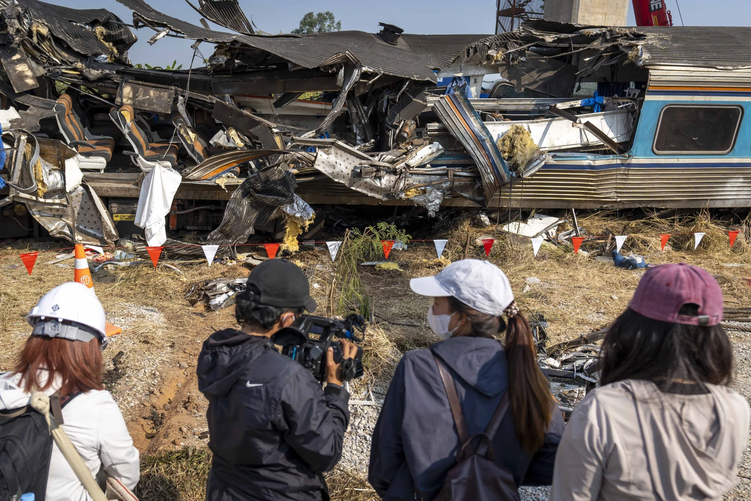  January 15, 2026: Members of the media shoot video and observe a heavily damaged train car which was crushed by a falling crane while the train was was moving underneath the Thai-Chinese high speed rail construction site, the morning after the trage