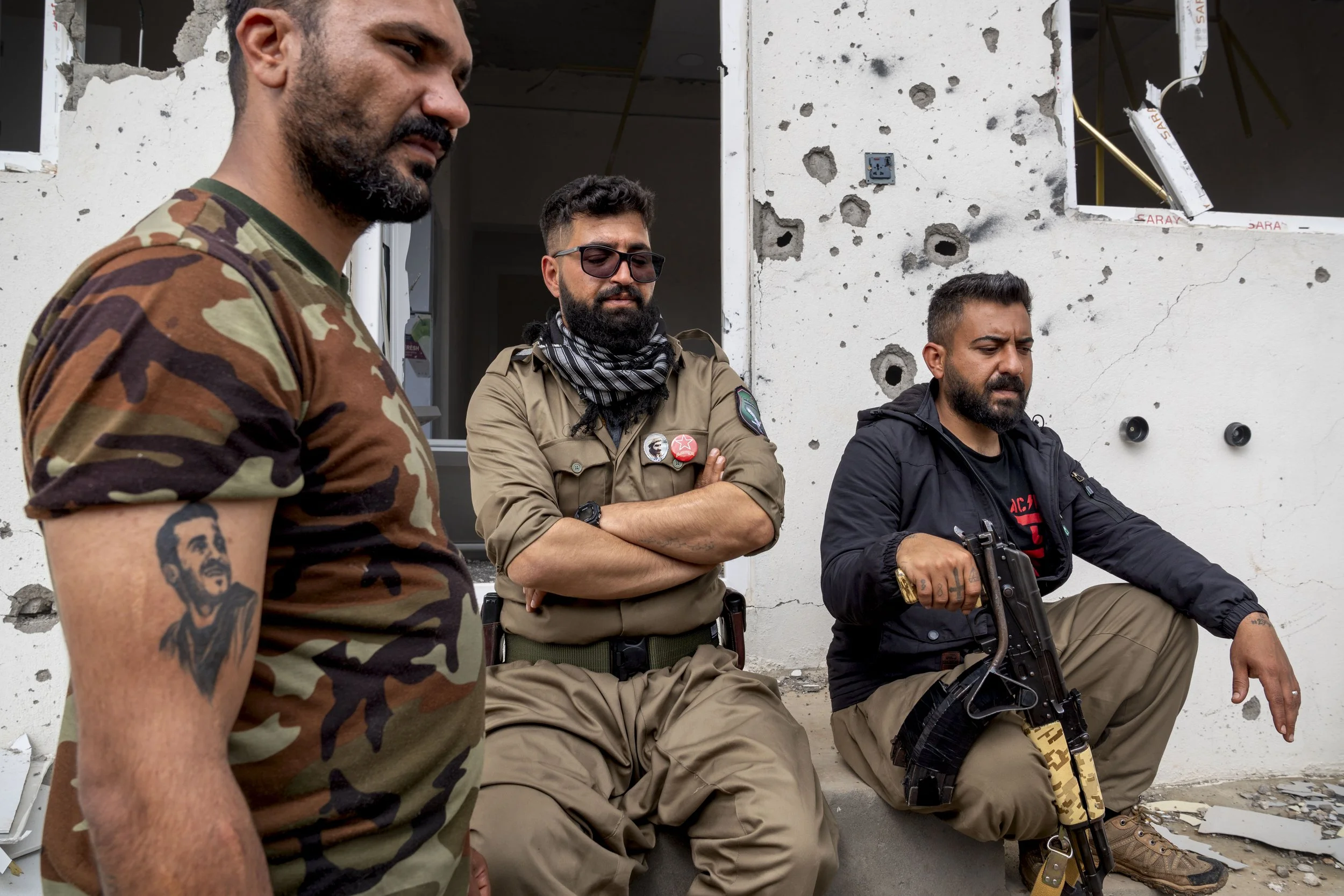  Three Komala fighters sit next to the shrapnel scared walls of their Surdash camp. 