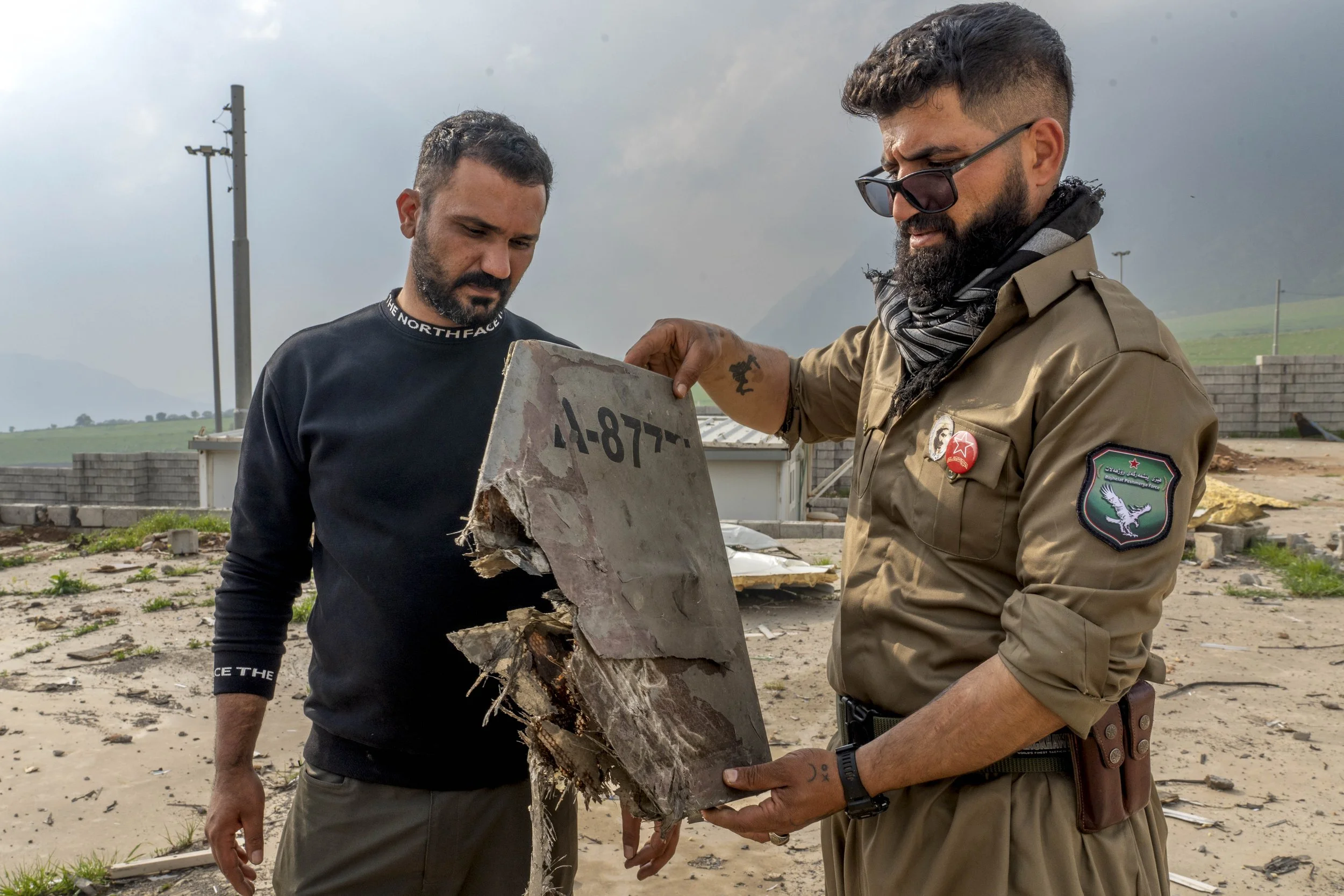  Two Komala members inspect a piece of the Iranian shahed drone that struck their camp of April 14, which critically injured and eventually killed Ghazal Moulan, 19, and wounded two others. 