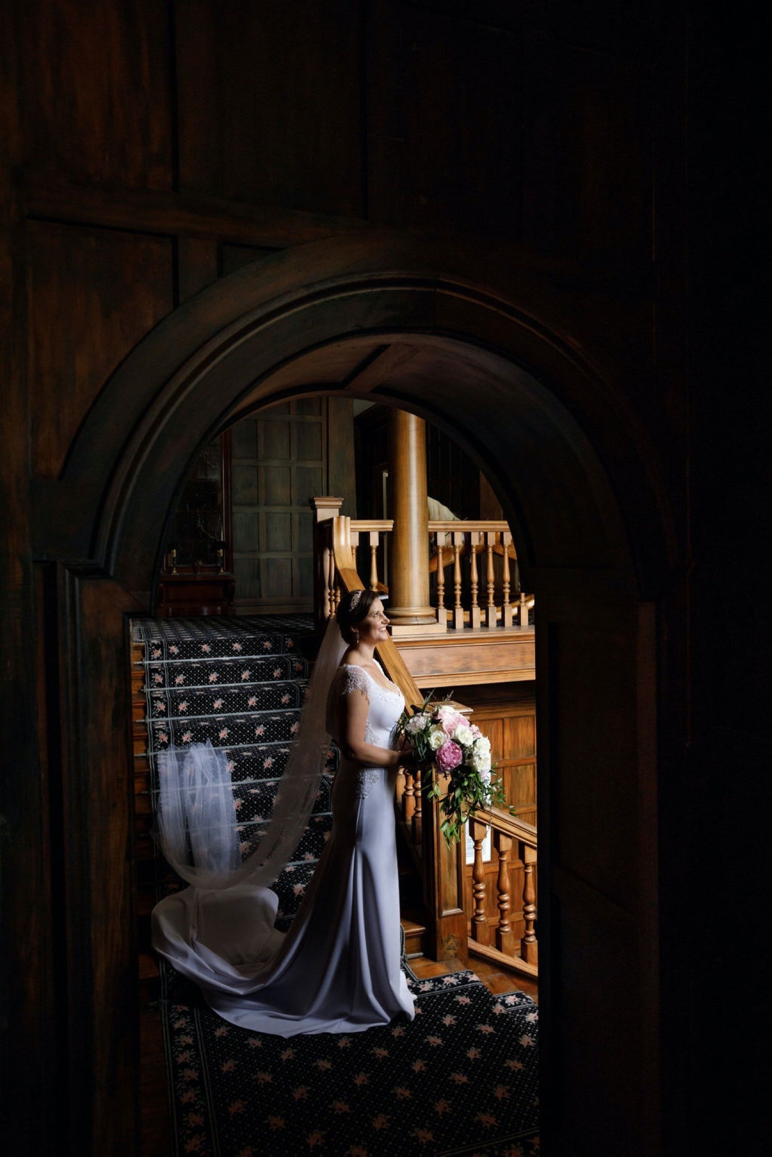 06_wairarapa-wedding-longwood-jessDewsnap07_Dramatic portrait of bride coming down old fashioned staircase, in contrasting light. .jpg