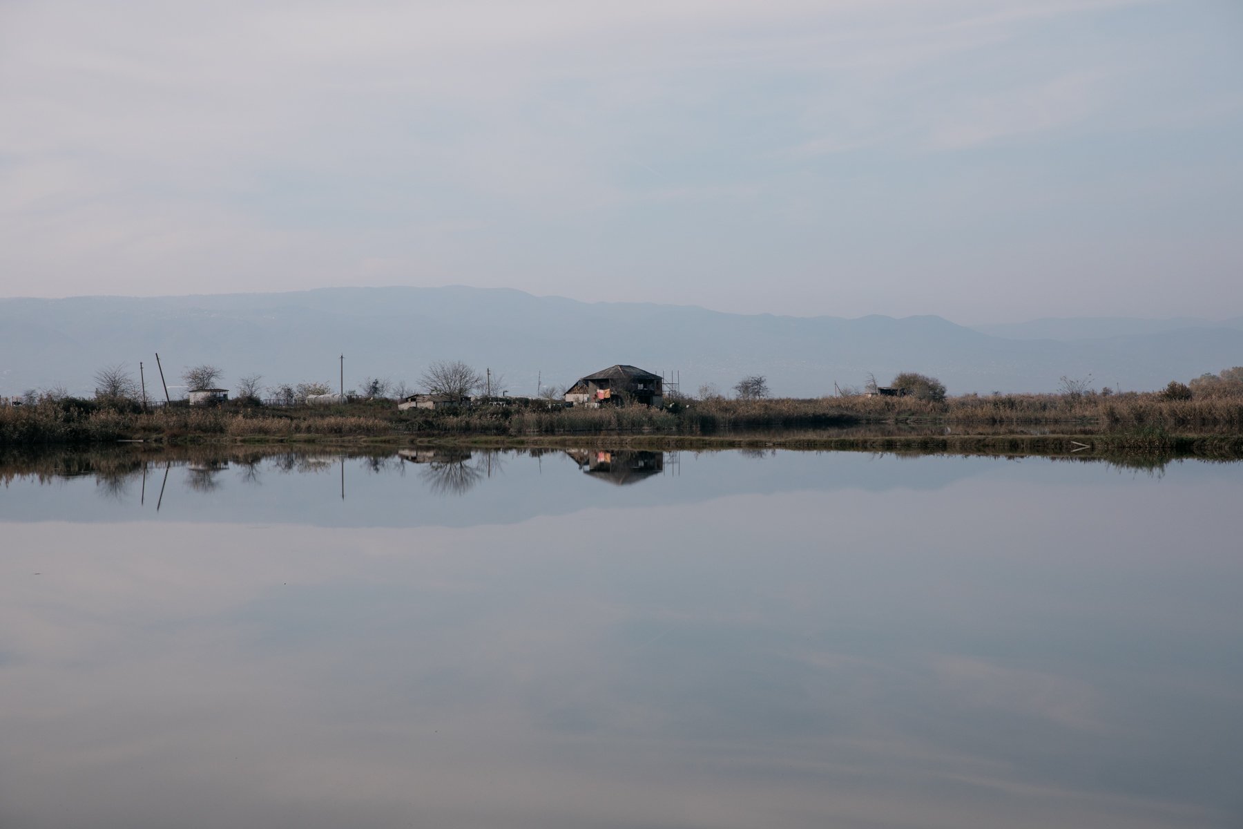  A house reflected in the still water of a reservoir used for irrigation. 