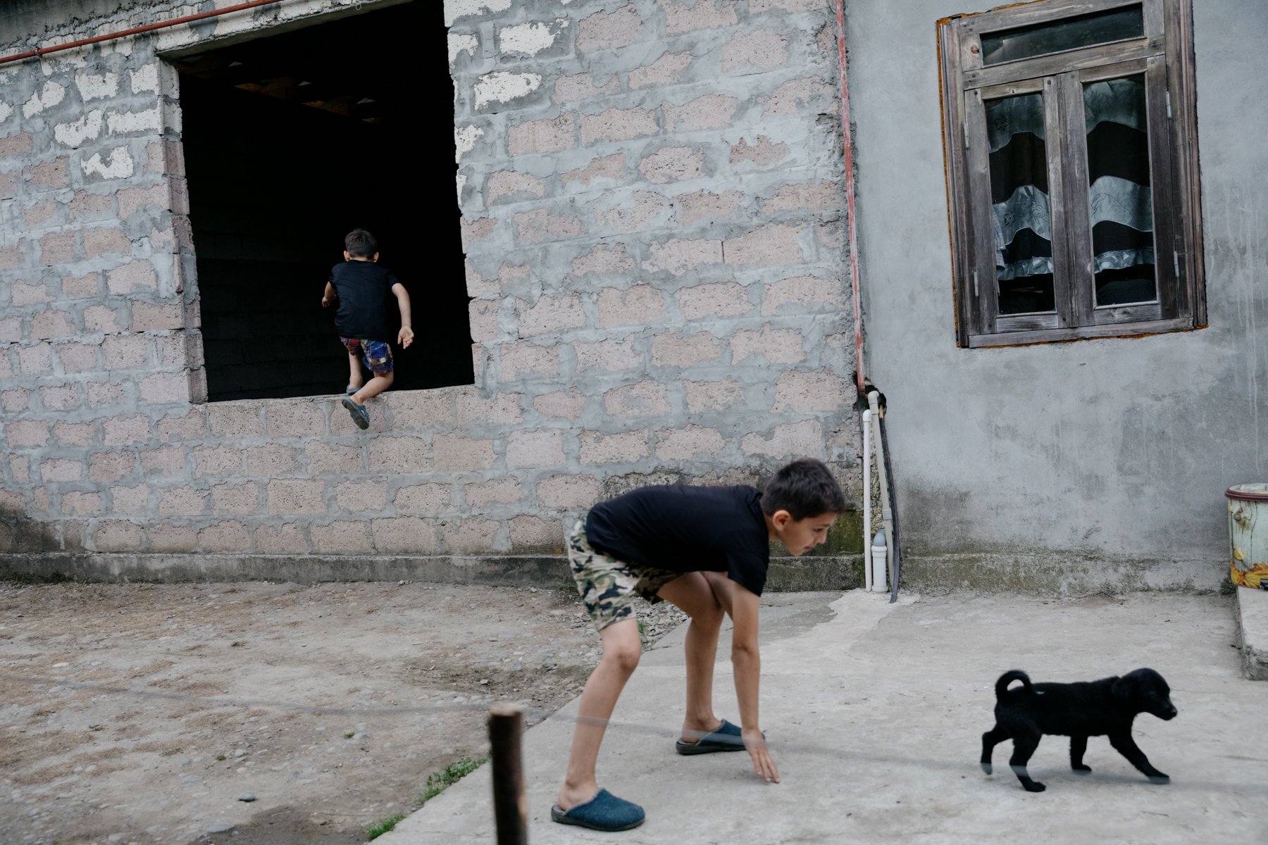 Brothers play as their new puppy explores their garden in Orsantia, directly beside the Enguri River. 