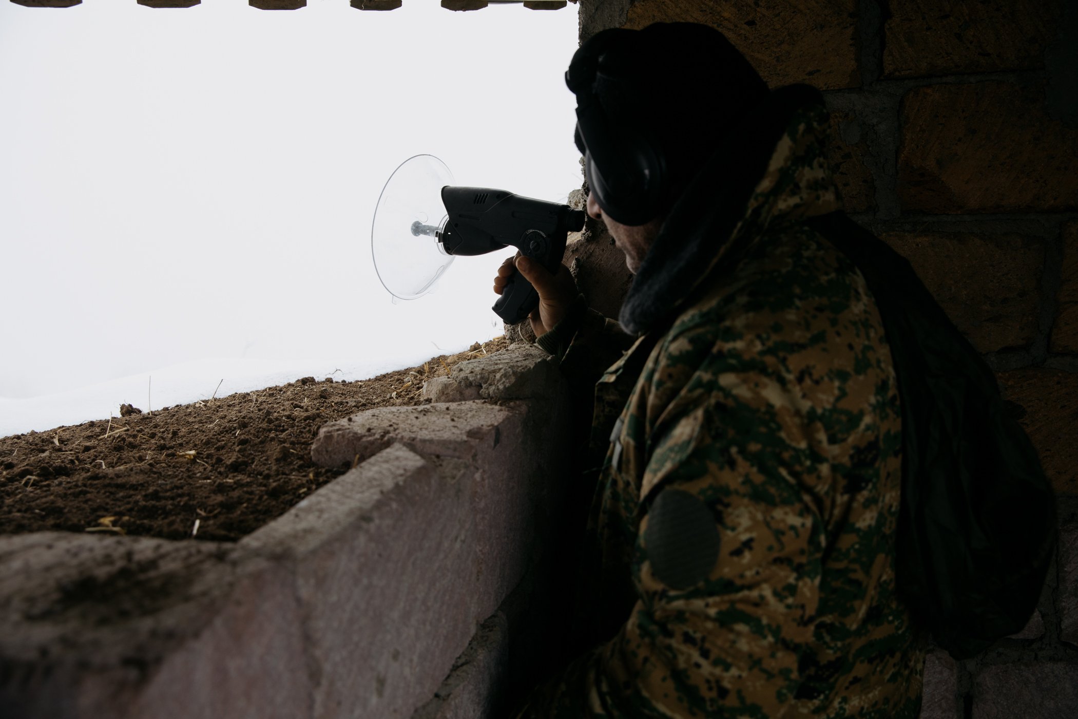  An Armenian soldier uses a long-range listening device as an Azerbaijani position 600 metres away is hidden by fog. 