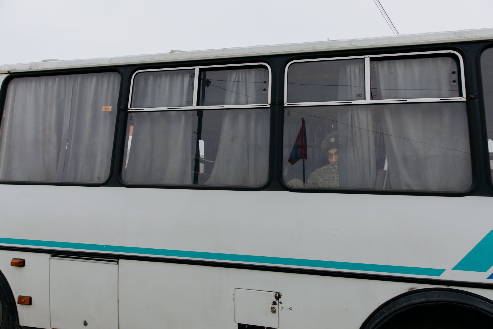  A Russian soldier peers from a bus window at the Tegh checkpoint as around 100 peacekeepers travel to Yerevan airport to return home. 