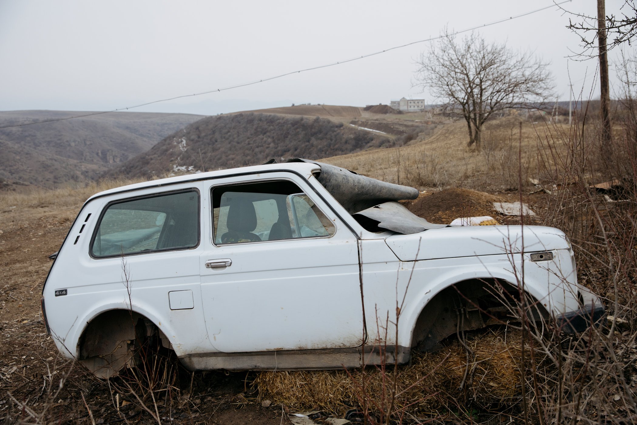  An abandoned Lada Niva on the edge of Nerkin Khndzoresk. In the background are new buildings belonging to Armenia's National Security Service, whose border guards patrol the edges of the village. 
