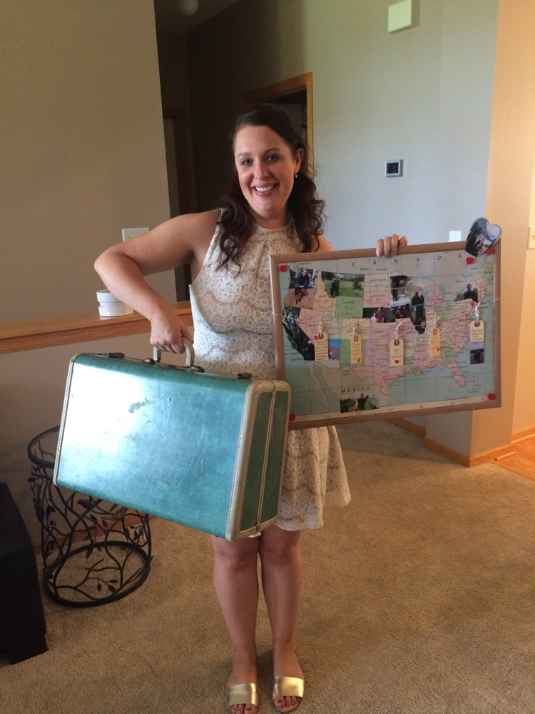  Bride at her travel themed bridal shower with vintage suitcase and map of places the couple has been. 