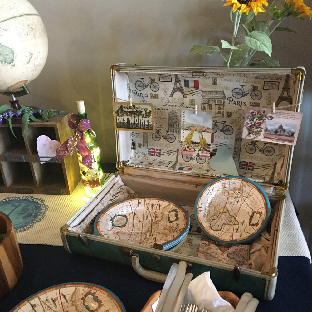  Vintage suitcase with globe plates and napkins for a travel themed bridal shower. 