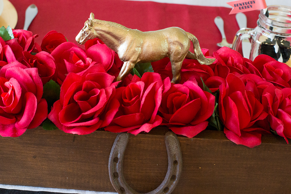  Wooden box with faux red roses, horseshoe, and gold spray painted toy horse makes a beautiful Kentucky Derby party centerpiece. 