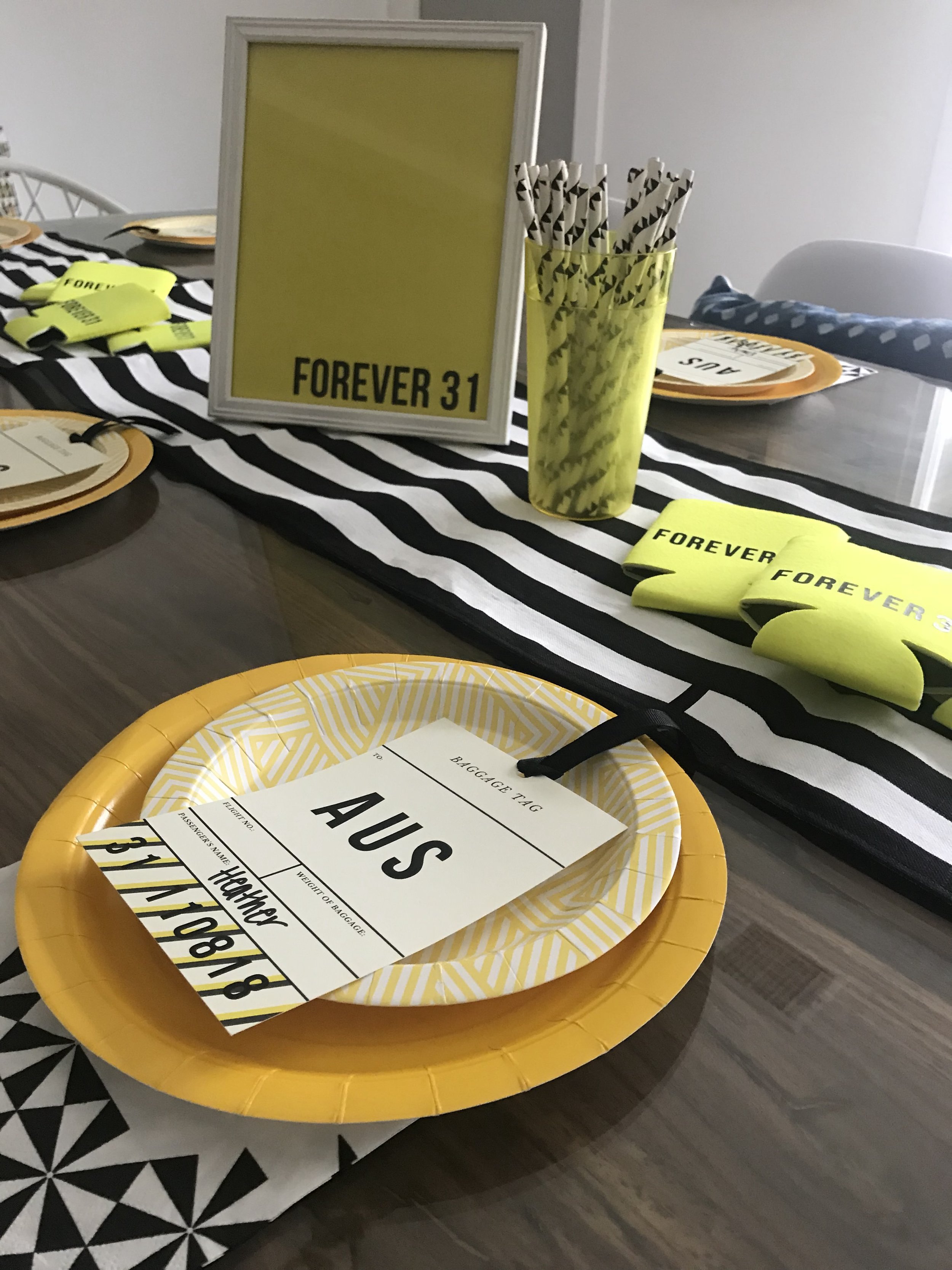  Yellow solid paper plates and geometric yellow plates along with black geometric paper straws and napkins. 
