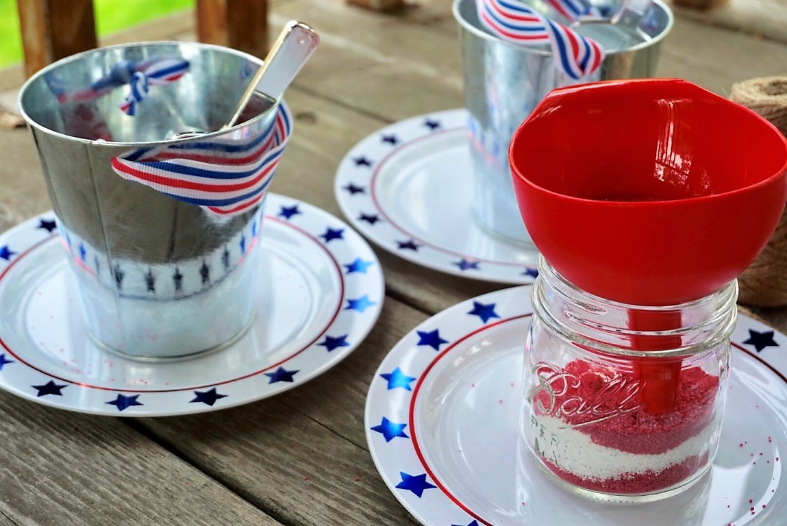  Use a funnel to put sand into Ball mason jars to make DIY sand art with kids at your 4th of July BBQ. 