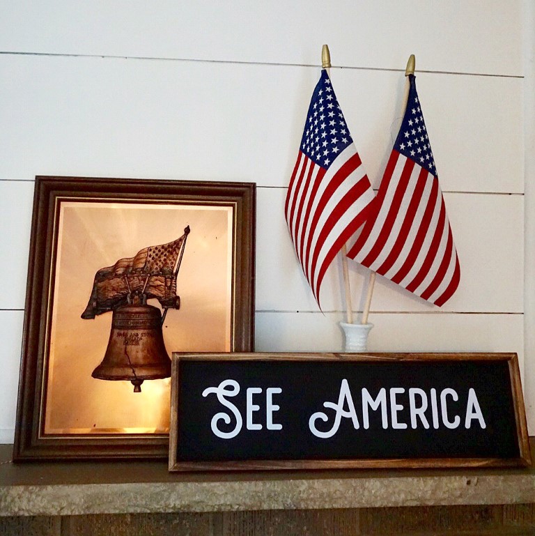 Copper liberty bell, American flags, and See America sign.