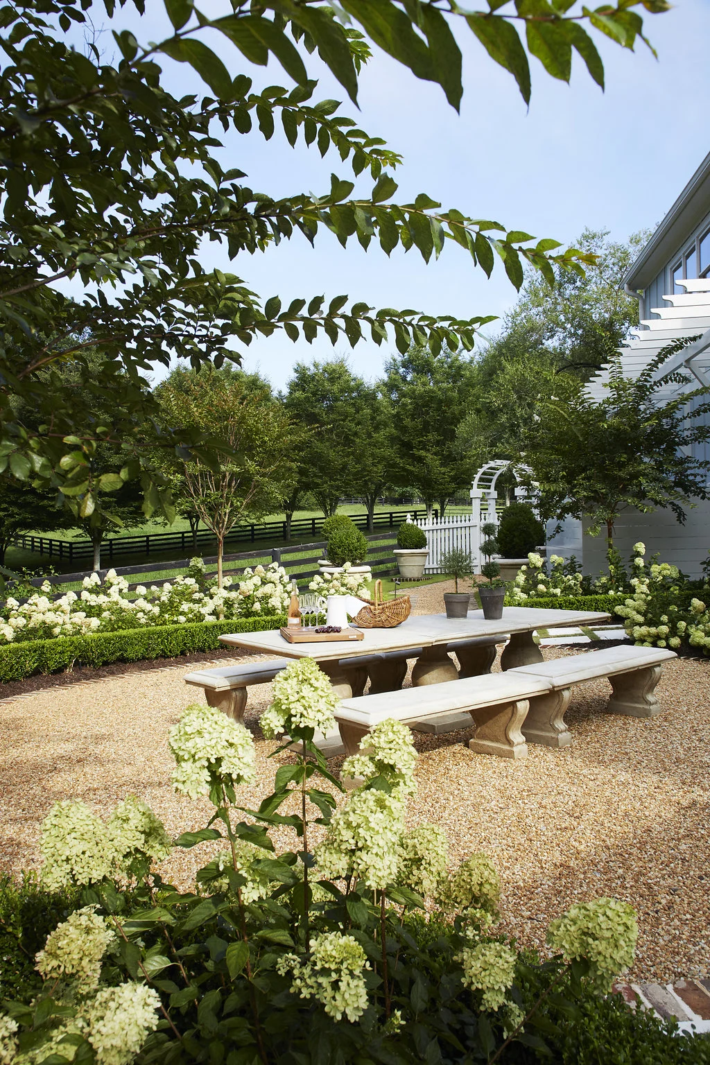 Hydrangea bushes and trees line the area around an outdoor entertainment area.