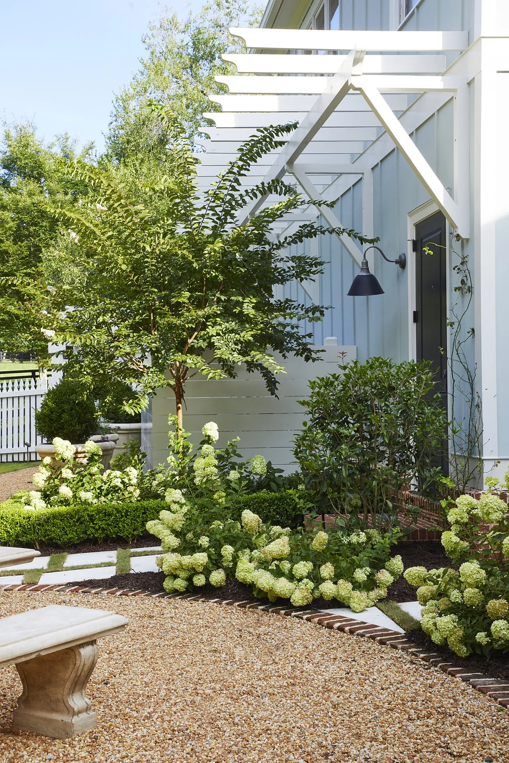 Hydrangea bushes and trees next to the entrance of the home.