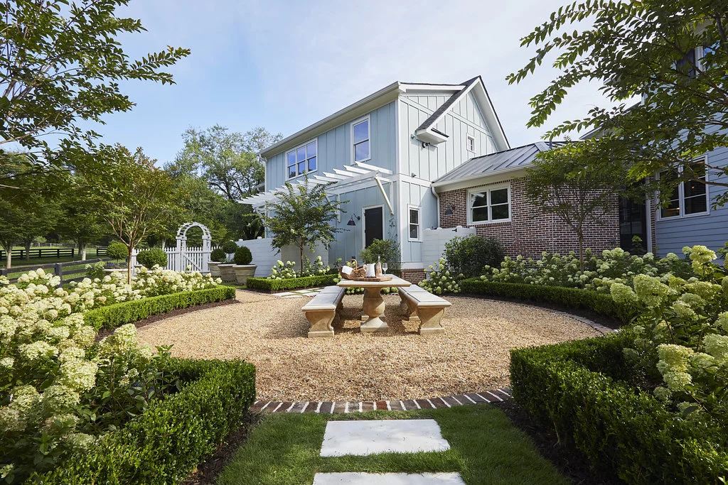 Entertainment area surrounded by a grass walkway and hydrangea bushes.