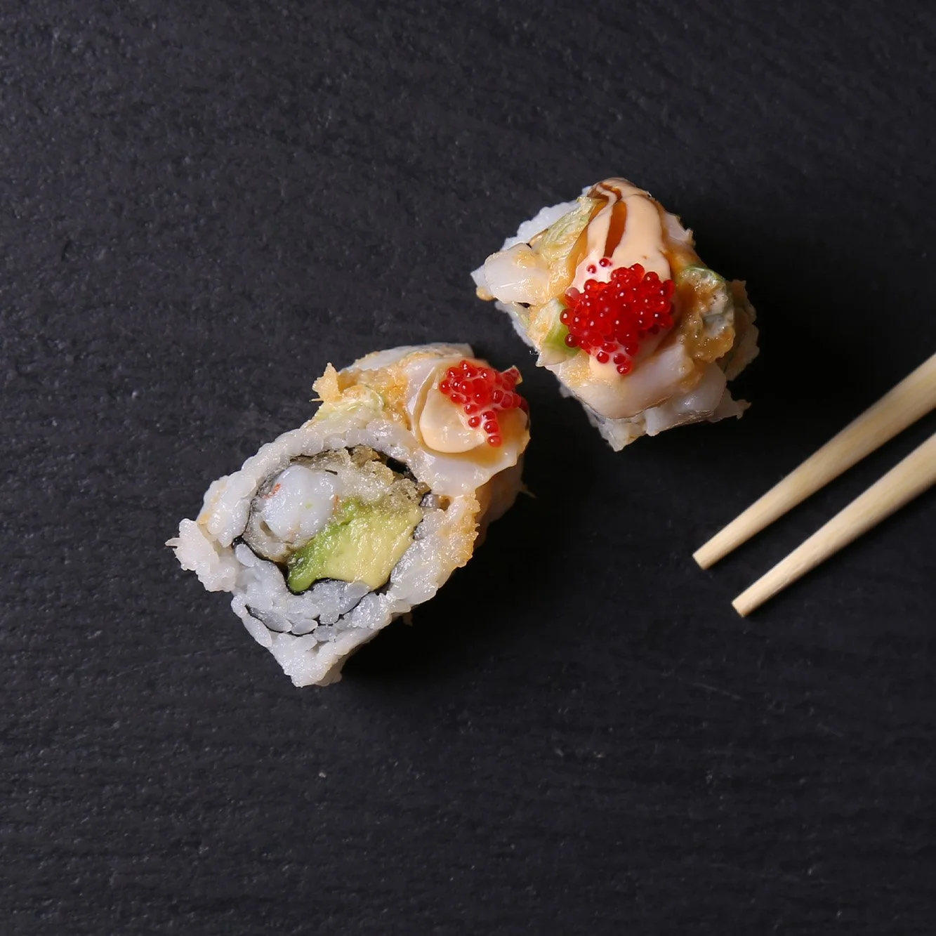 Deux sushis avec des baguettes sur ardoise noire