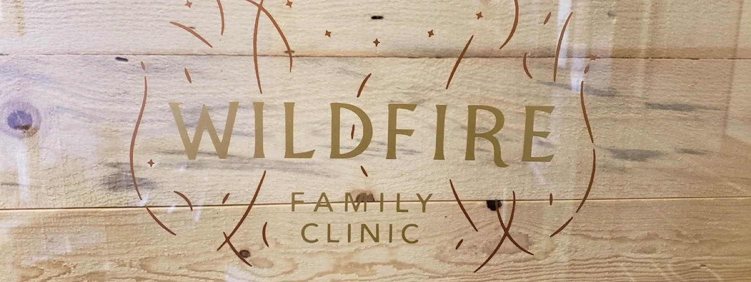 wildfire family clinic logo on glass in front fo wood wall