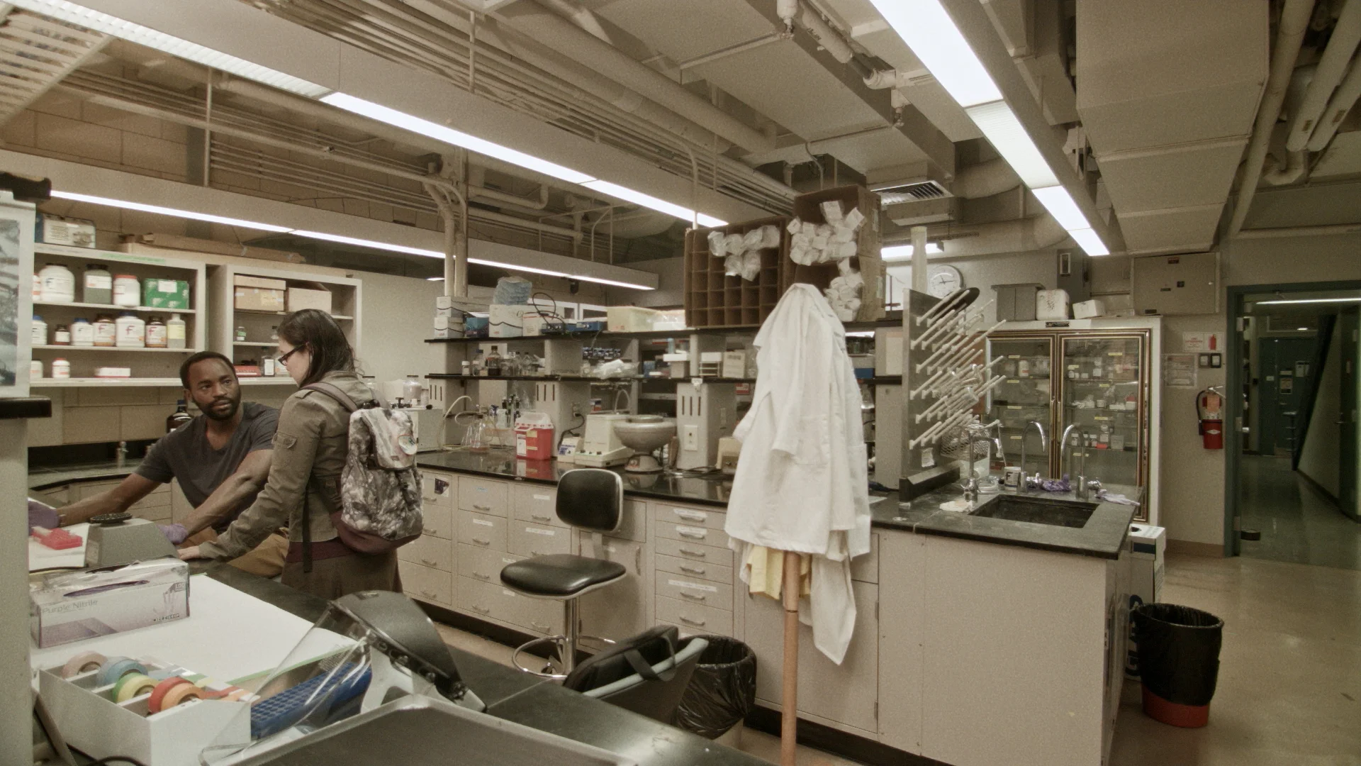 Still from ANYA with DR. SEYMOUR LIVINGSTON (Motell Foster) and RIKA ENDO (Olivia Oguma) in Dr. Andreas Phenning’s lab. Still from ANYA by Jacob Okada.