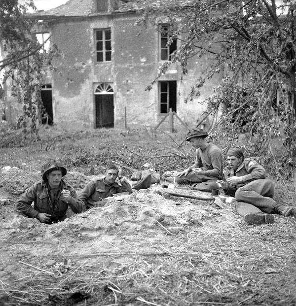 Des soldats du Highland Light Infantry of Canada prenant leur petit-déjeuner à Buron, en France, le 9 juillet 1944, le lendemain de leur prise du village (Lieut. Michael M. Dean / Canada. Ministère de la Défense nationale / Bibliothèque et Archives Canada / PA-131399 ).