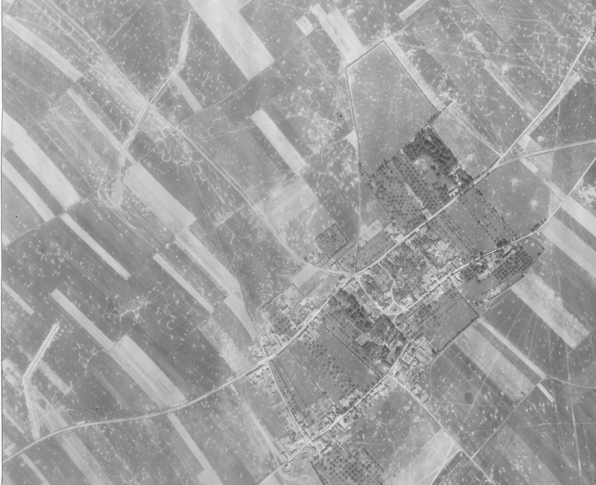 Une photo de reconnaissance aérienne de Buron, prise le 24 juin 1944, montrant clairement les fossés antichars que les Allemands ont construits pour la défense du village. Les traces de chars et les cratères indiquent les violents combats dans la région (LCMSDS Air Photo Collection 307/408…