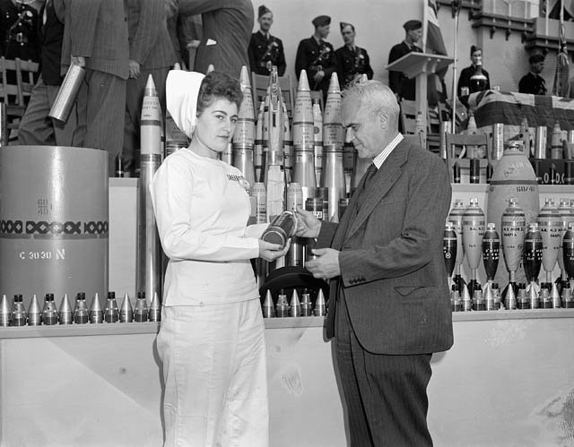  Female worker of the Defence Industries Limited plant. Edna Poirier presenting to Hon. C.D. Howe the 100,000,000th projectile manufactured at the Cherrier plant 